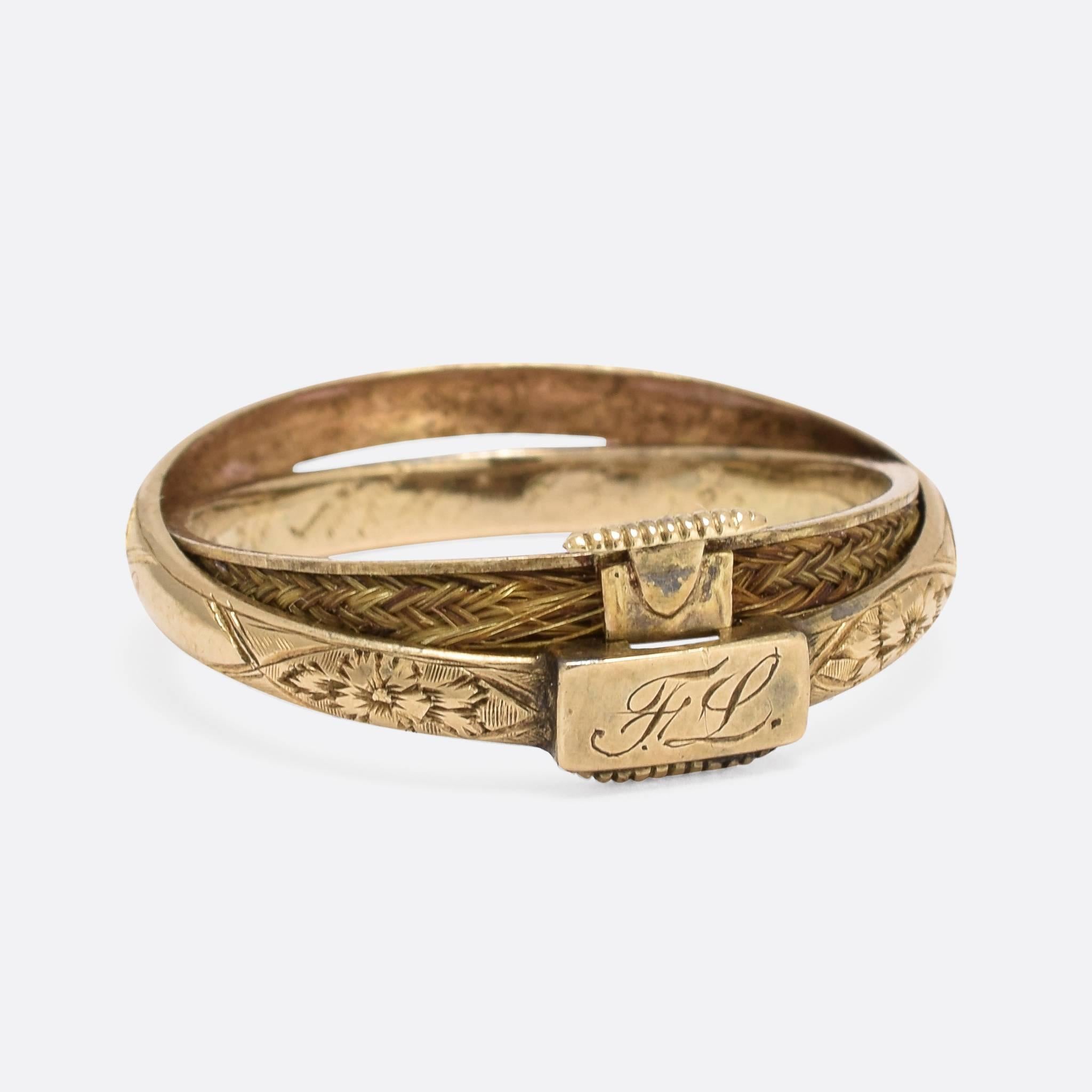 This most unusual Victorian mourning ring has been made with a gimbal action, allowing the inner ring to open and reveal a secret compartment. Inside is an intricately woven lock of hair, and the front panel is engraved with the initials FL. The