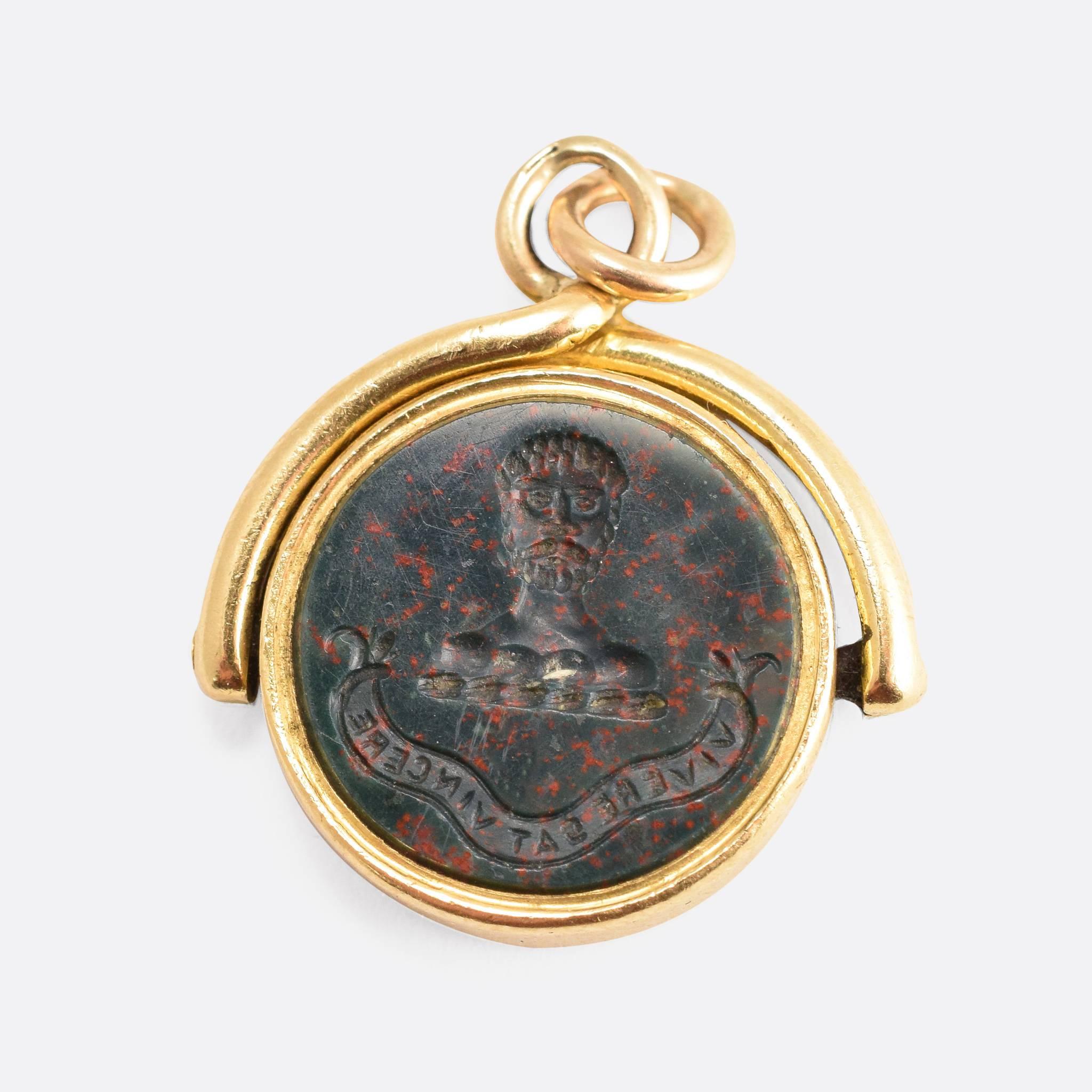 This attractive antique spinner fob is set with two carved stone panels: one bloodstone, the other carnelian agate. Each panel is carved with a heraldic crest, above Latin motto. The words read 