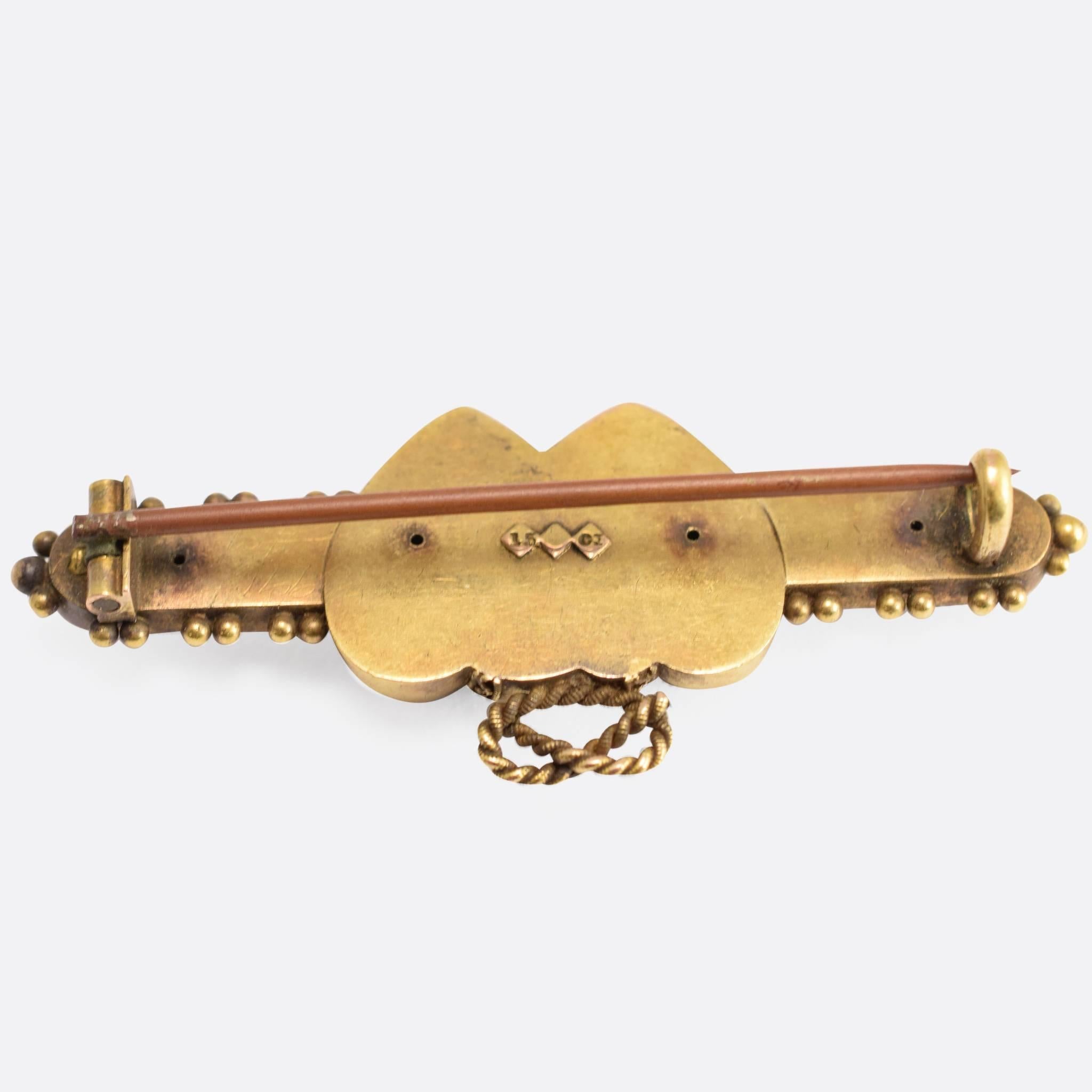 This lovely antique brooch is modelled in 15ct gold, with a Double Heart centrepiece crowned with a Lover's Knot. There is Etruscan-style applied gold detail throughout, with coiled rope and pommels. An old cut diamond is nestled in the space where