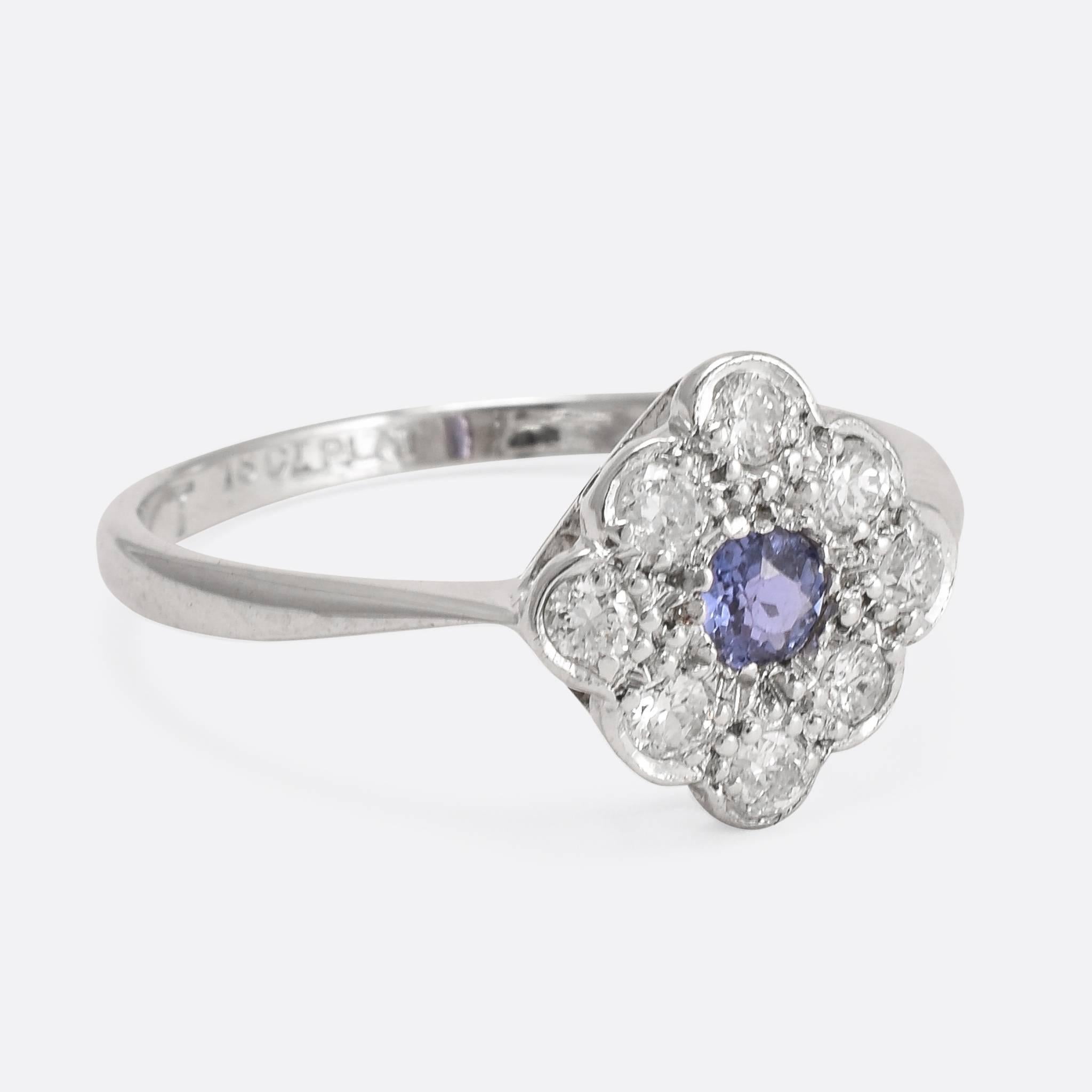 This pretty cluster ring is set with a superb cornflower sapphire, and eight bright brilliant cut diamonds. The simple 18ct white gold band features elegant pinched shoulders, with platinum settings on the head. A dainty ring, full of Art Deco