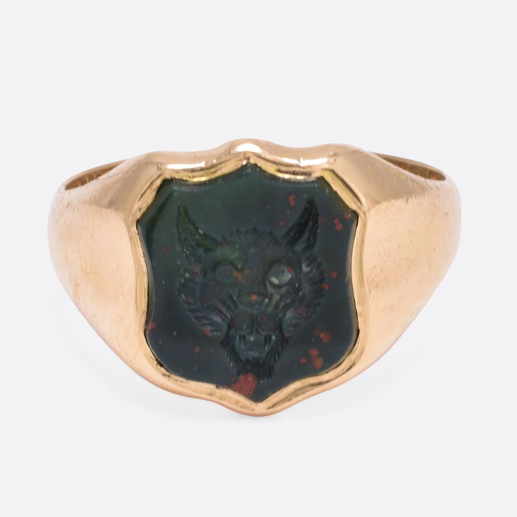 This cool antique Signet Ring is set with a shield-shaped bloodstone panel, carved with an English heraldic crest. Depicted is the face of a wolf - a crest that was adopted by the Sharpe family. It's modelled in 18ct gold, with Birmingham hallmarks
