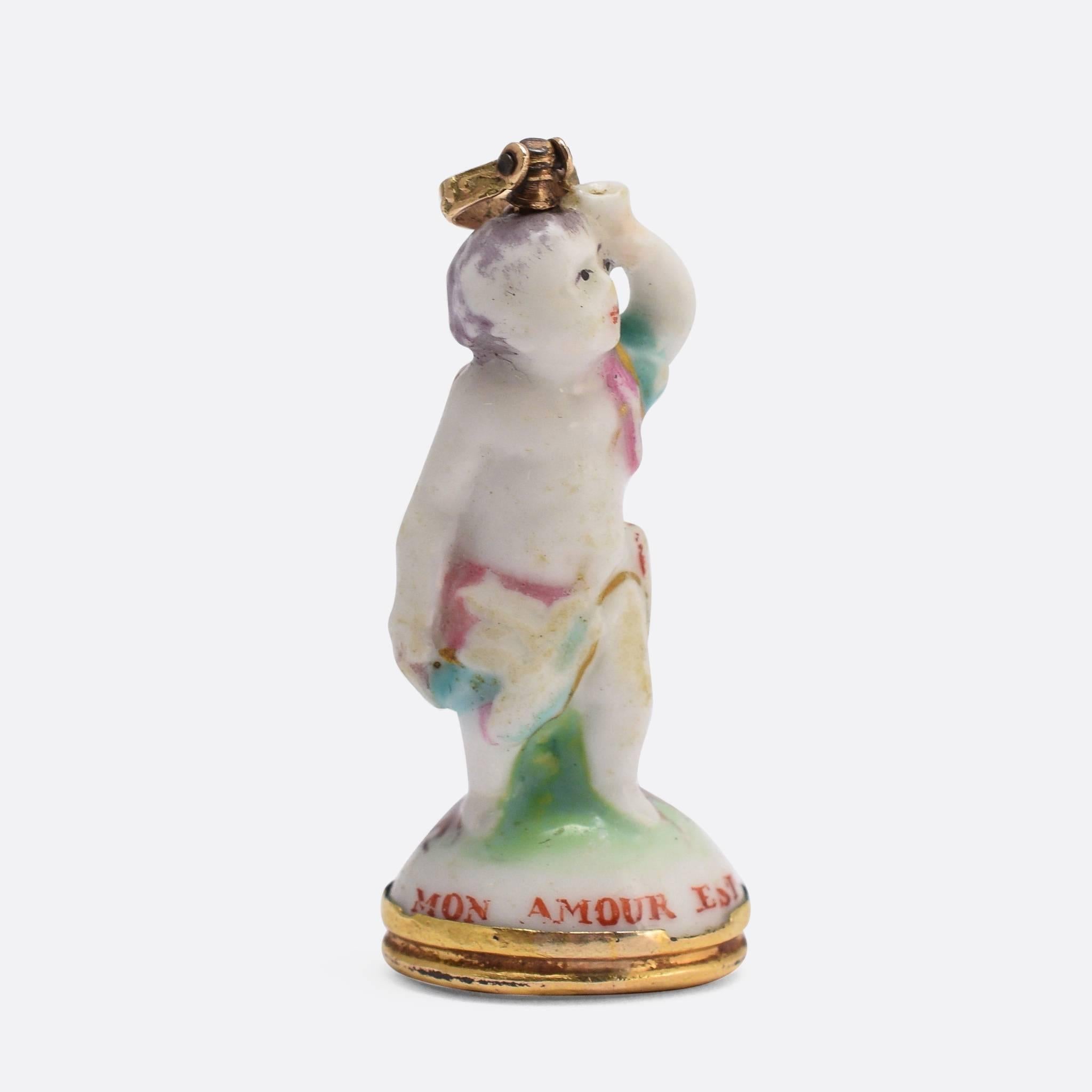 An original 18th Century porcelain Derby Chelsea period fob seal. This particular piece features Cupid on a tree-stump holding a cup, and displays the pale colouring typical of the Chelsea factory. The original gold bail and seal base are both