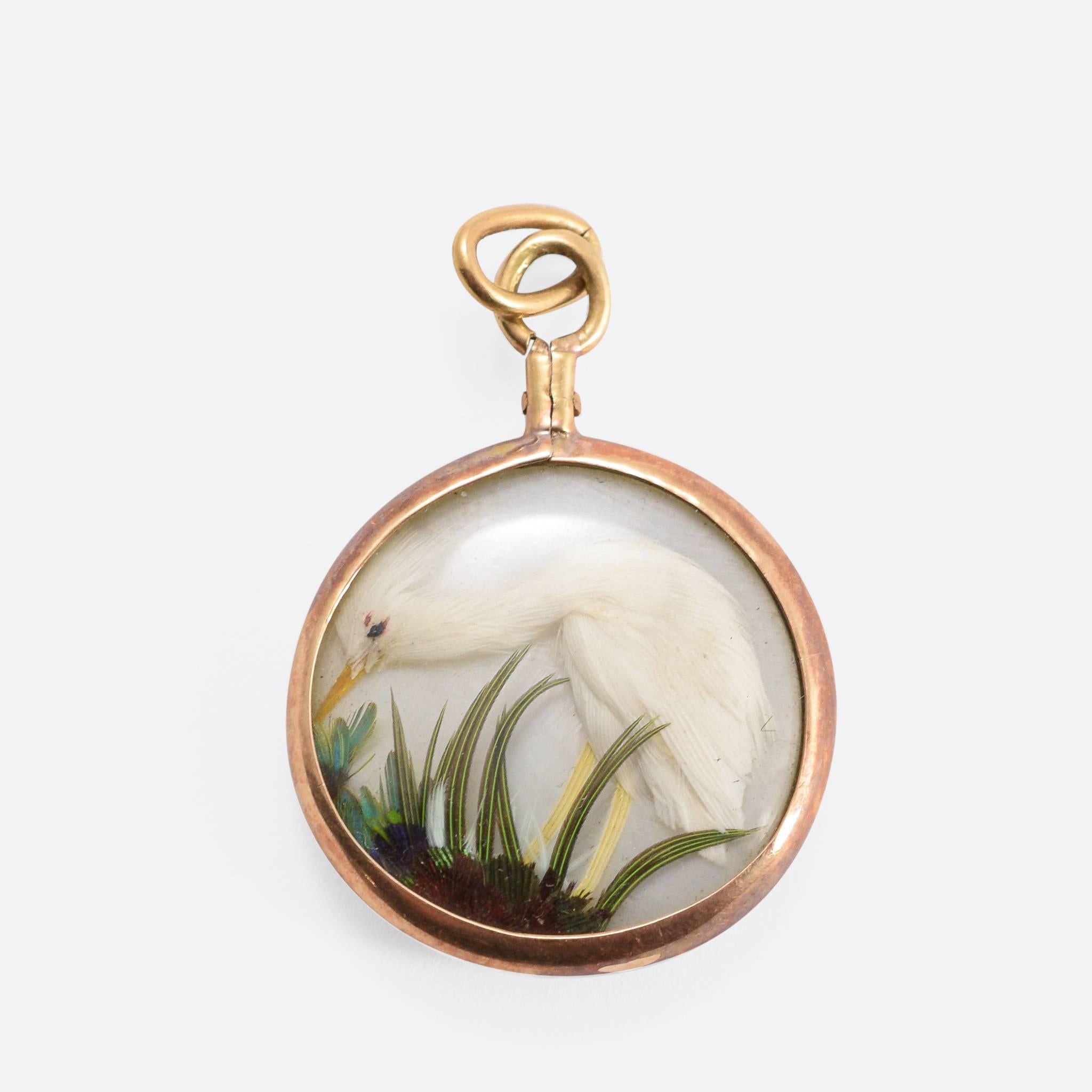 A cool and unusual Victorian pendant, c.1890. One each side, behind glass, is a little bird - seemingly made from the feathers of its real-life model. A glorious peacock on one side, and an elegant white egrit on the other. Modelled in 15ct gold. 