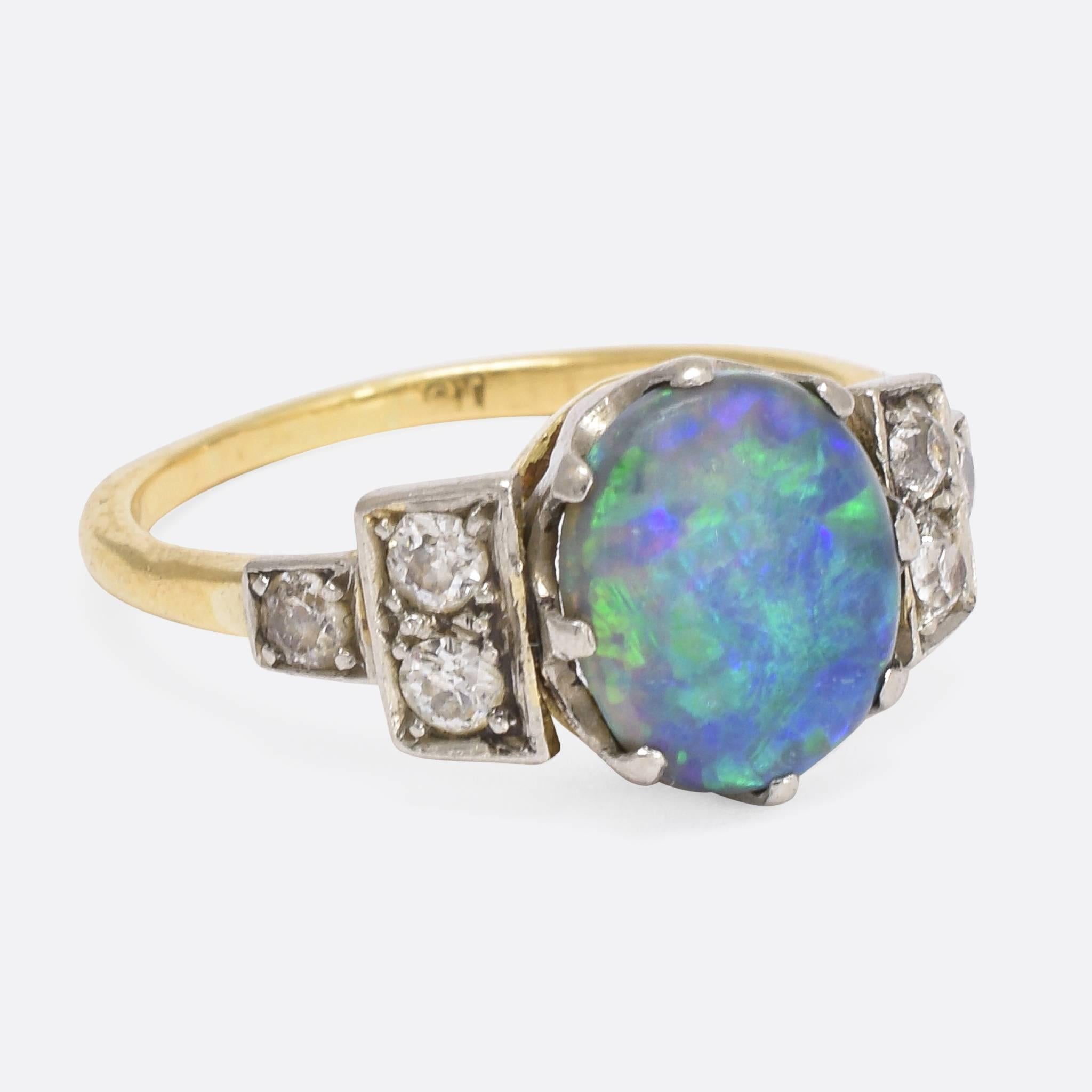 This superb Black Opal and Diamond ring was made in the Art Deco era, c.1930. The vibrant central stone displays deep blues, and flashes of green and purple - with old cut diamonds accenting the shoulders. An fine quality ring, full of character and