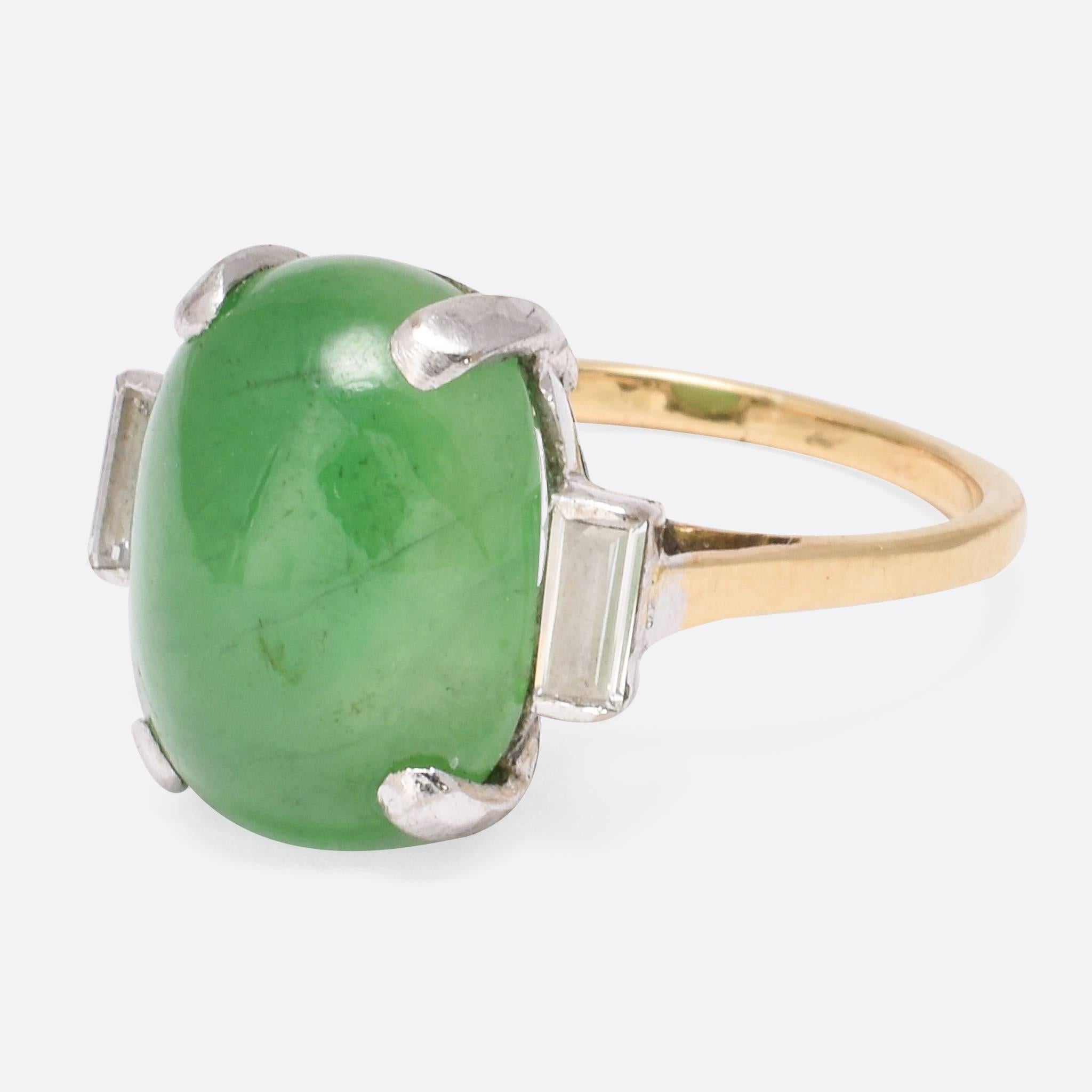 A stylish Art Deco three-stone ring, set with a superb jadeite cabochon flanked by two perfect baguette cut diamonds. The jade is of excellent colour - a vibrant apple green - and set in an oversized four-claw mount. Ring size: 6.75, Jade: 14.2 x