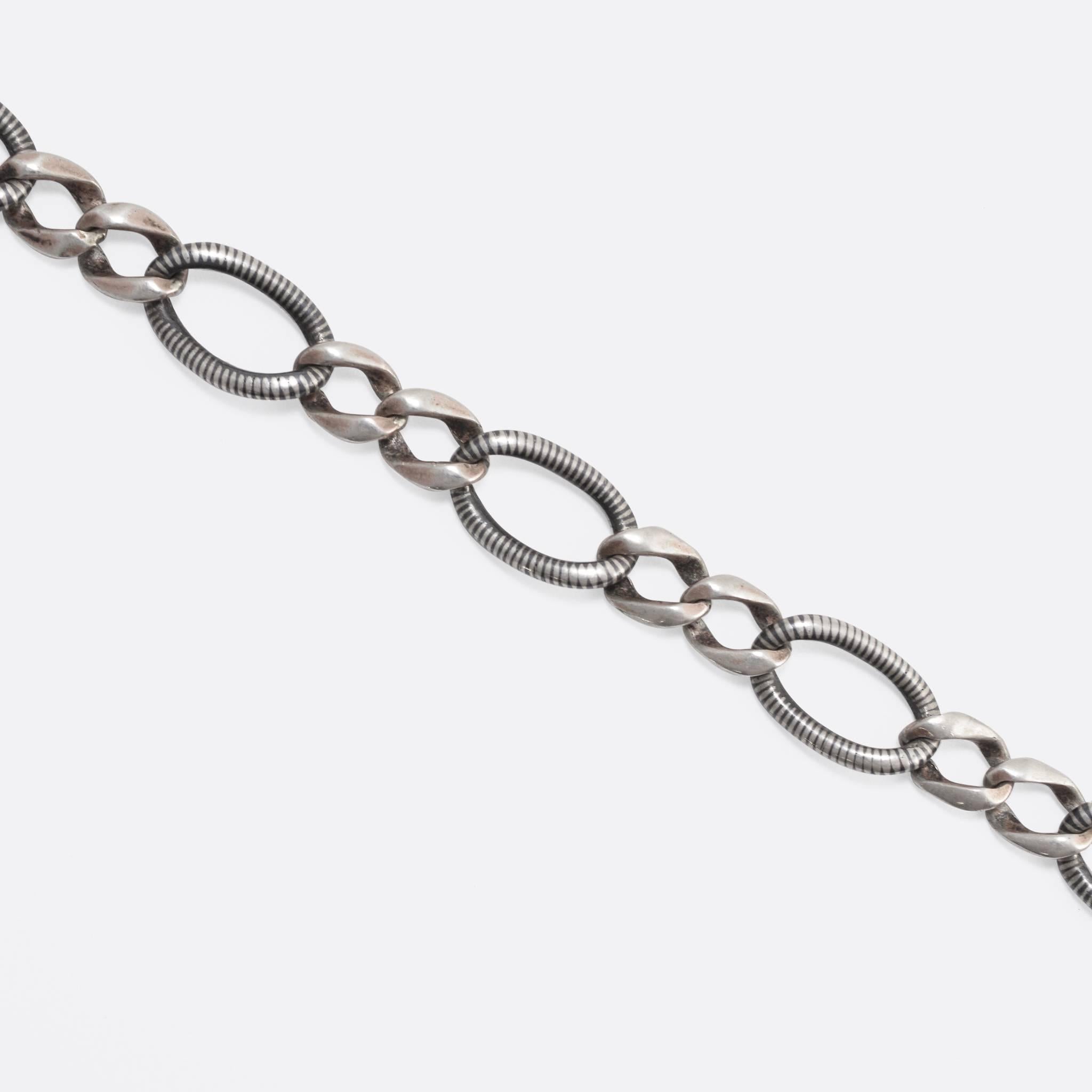 This lovely 1920s niello silver chain is likely of German origin, and features stylish curb links: the pattern is one niello link followed by two smaller silver links. Niello is a black mixture of silver, copper and lead sulphides, which in this