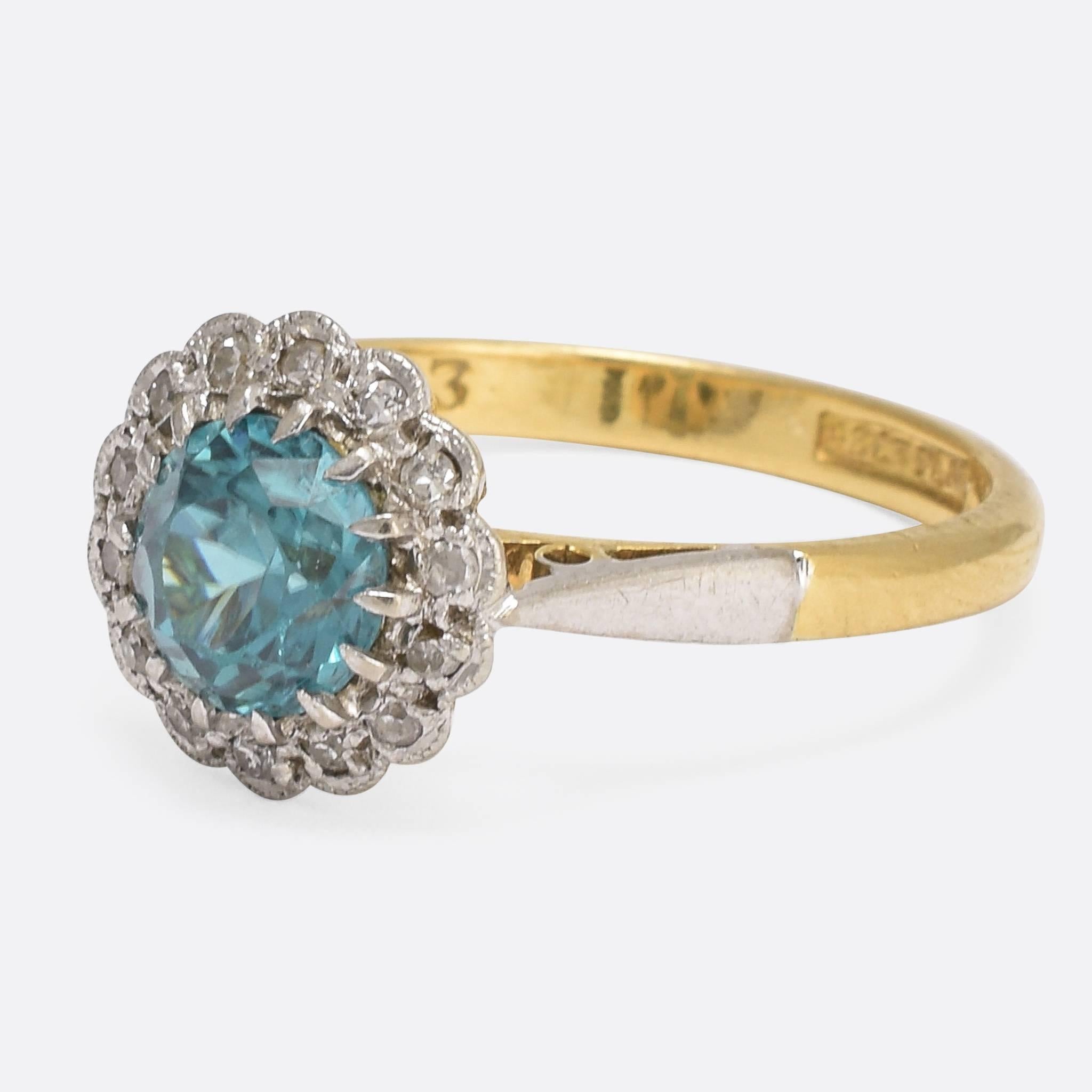 This pretty vintage cluster ring is set with a vibrant blue zircon in the centre of a diamond halo, the settings formed to look like flower petals. In typical Art Deco style, the head and shoulders are finished in platinum, with fine millegrain