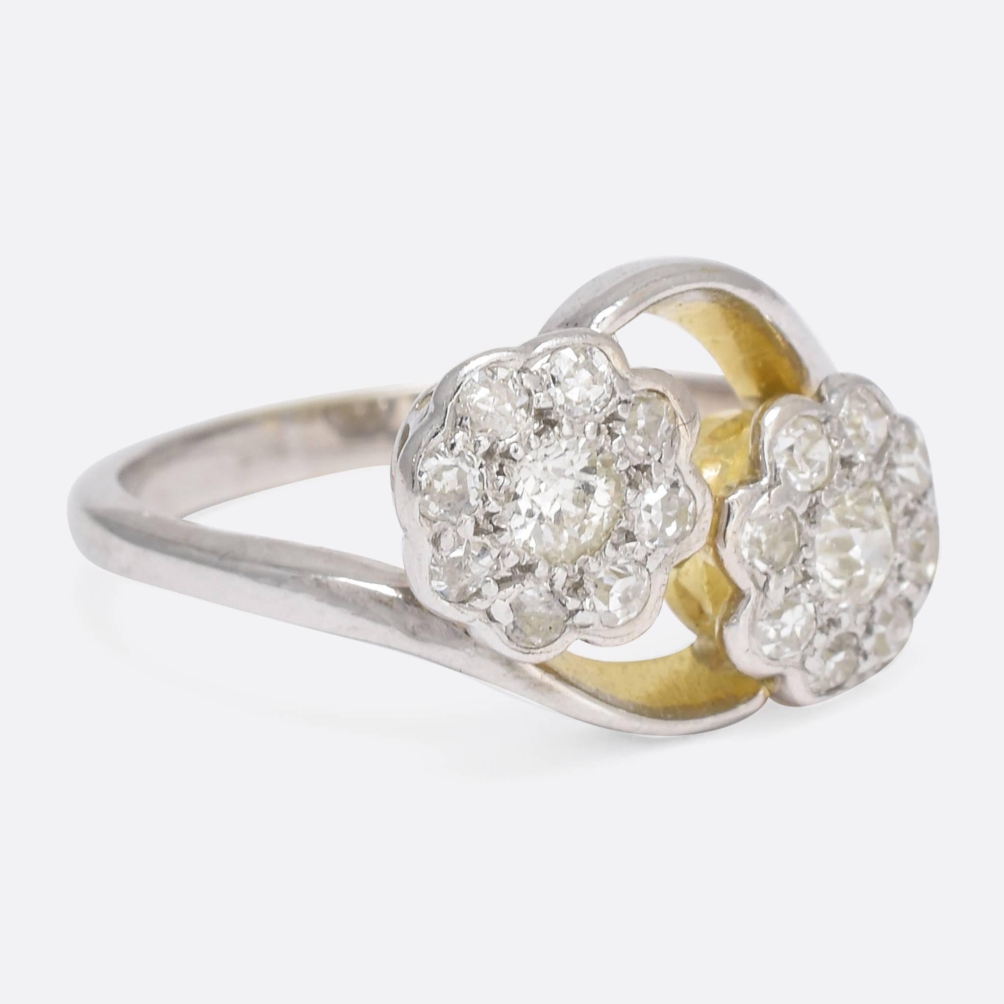 This delicate antique cluster ring has been modelled in the popular double daisy style. The offset head is graced by elegant crossover shoulders, and home to a .36 carat cluster of white diamonds. The ring itself is crafted in two-tone 18k gold -