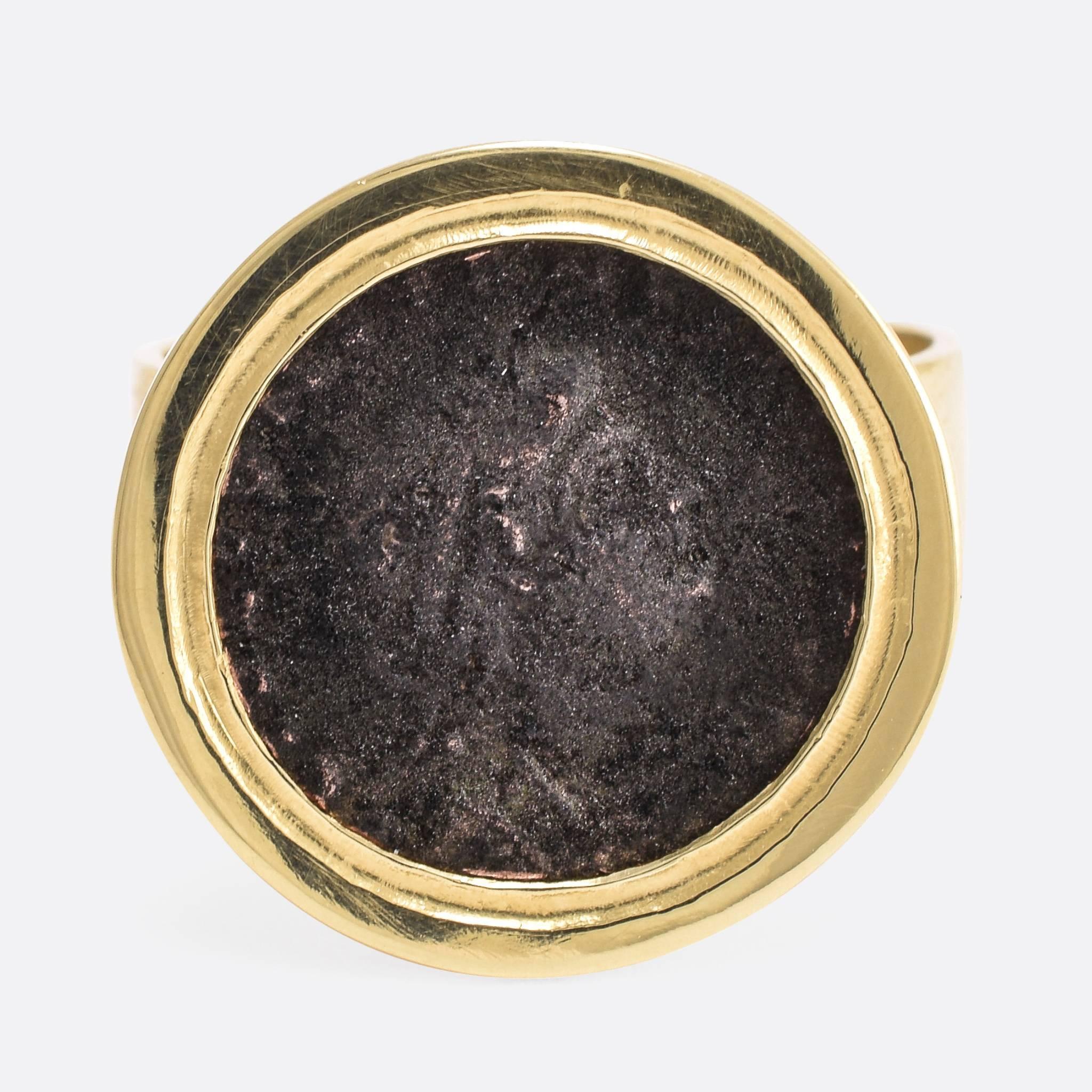 This cool Georgian signet ring has been set with an ancient Roman coin. The ring mount is modelled in 18k yellow gold, finely worked with an open back to display the reverse of the coin as well as the head side. The coin is a bronze Siliqua, with a