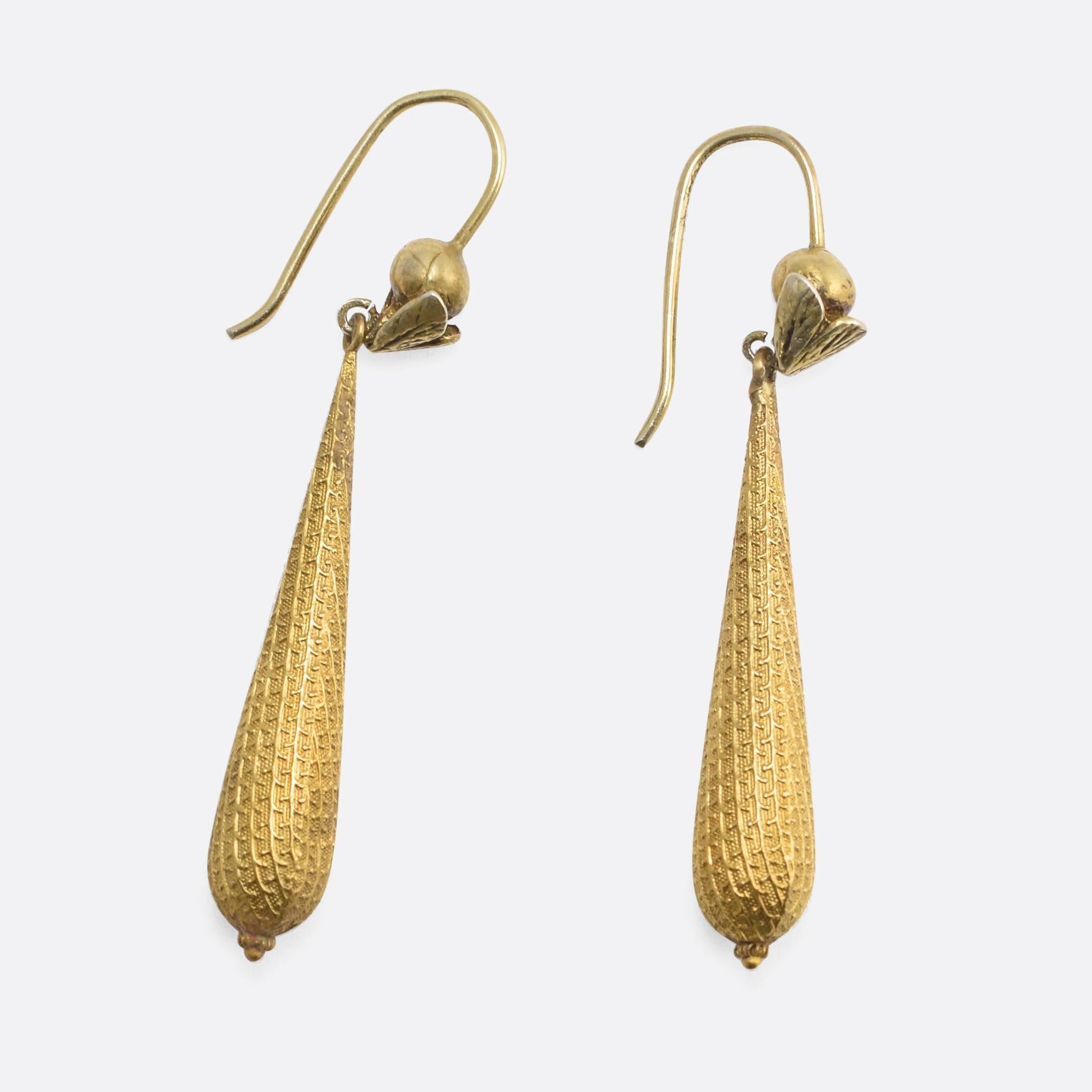 This wonderful pair of torpedo earrings is modelled in rich 15k yellow gold; they feature a finely textured surface, with a repeating stylised leaf & branch motif. The wires were likely added later, with ball tops and applied leaves. The pair remain