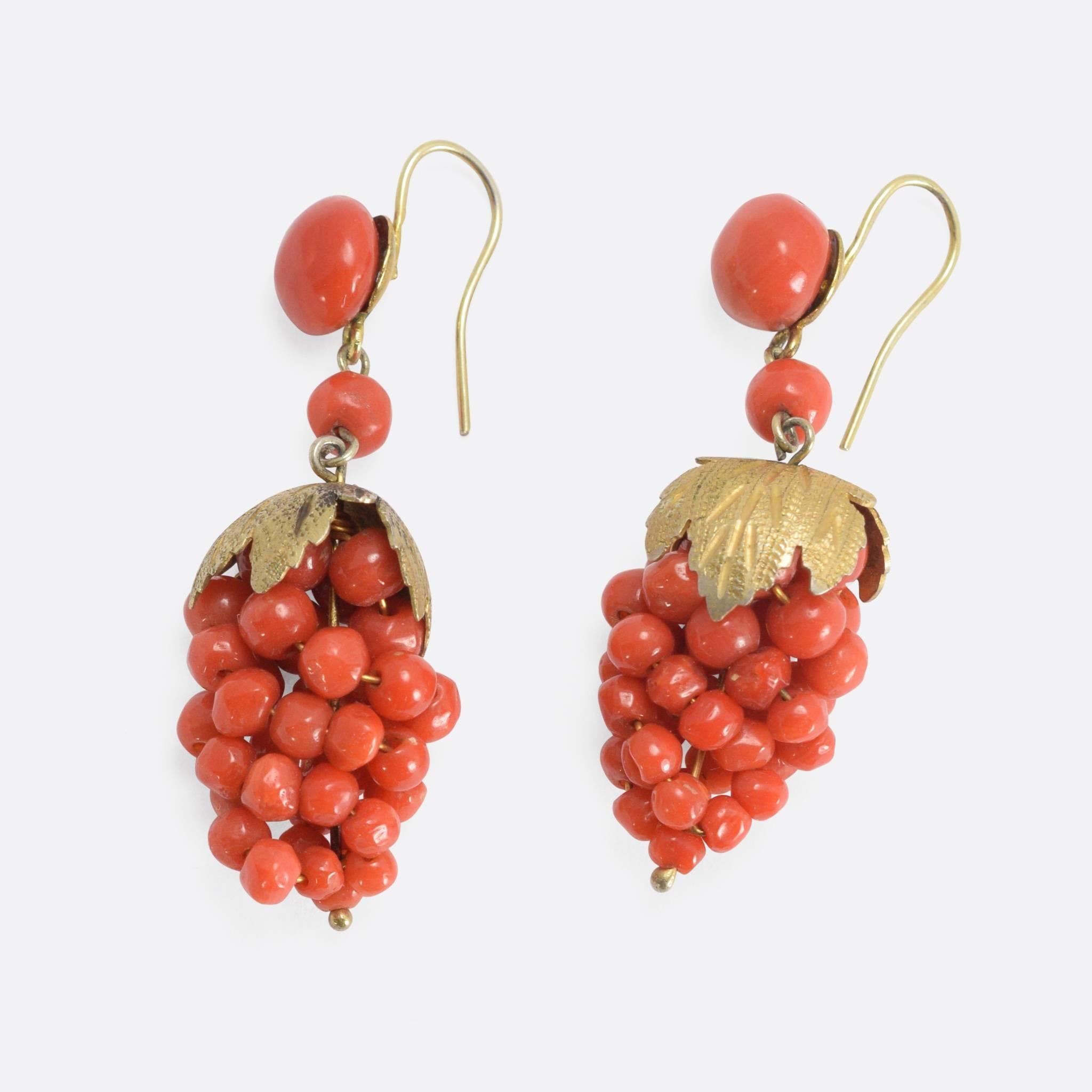 This charming pair of antique earrings dates to the mid-Victorian period. Featuring vivid orange coral balls, each earring is modelled as bunch of grapes, complete with a leaf fringe and two larger coral orbs above. The wires are 9k yellow gold, and