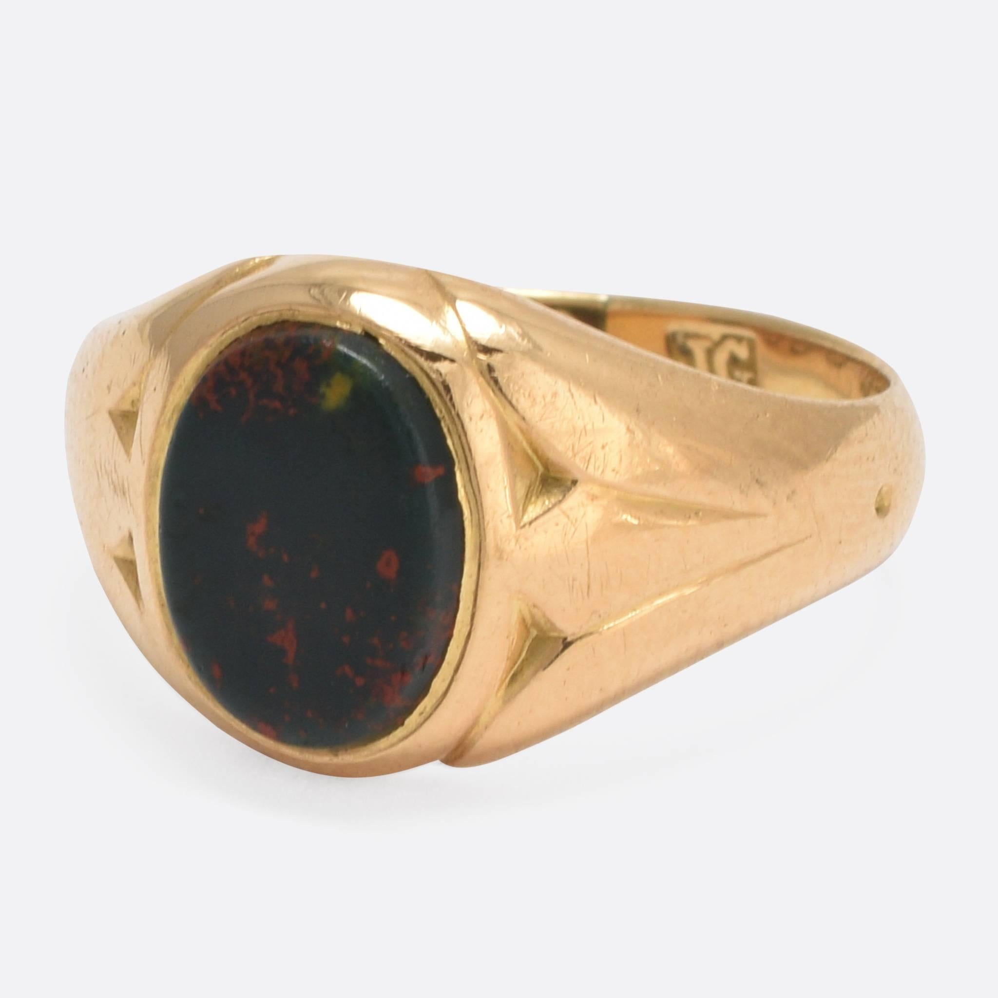 This stylish antique signet ring is set with an oval bloodstone agate panel that remains uncarved. The shoulders feature subtle detailing, and the piece bears clear Chester hallmarks for 18k gold and the year 1900. A lovely, smaller scale piece,
