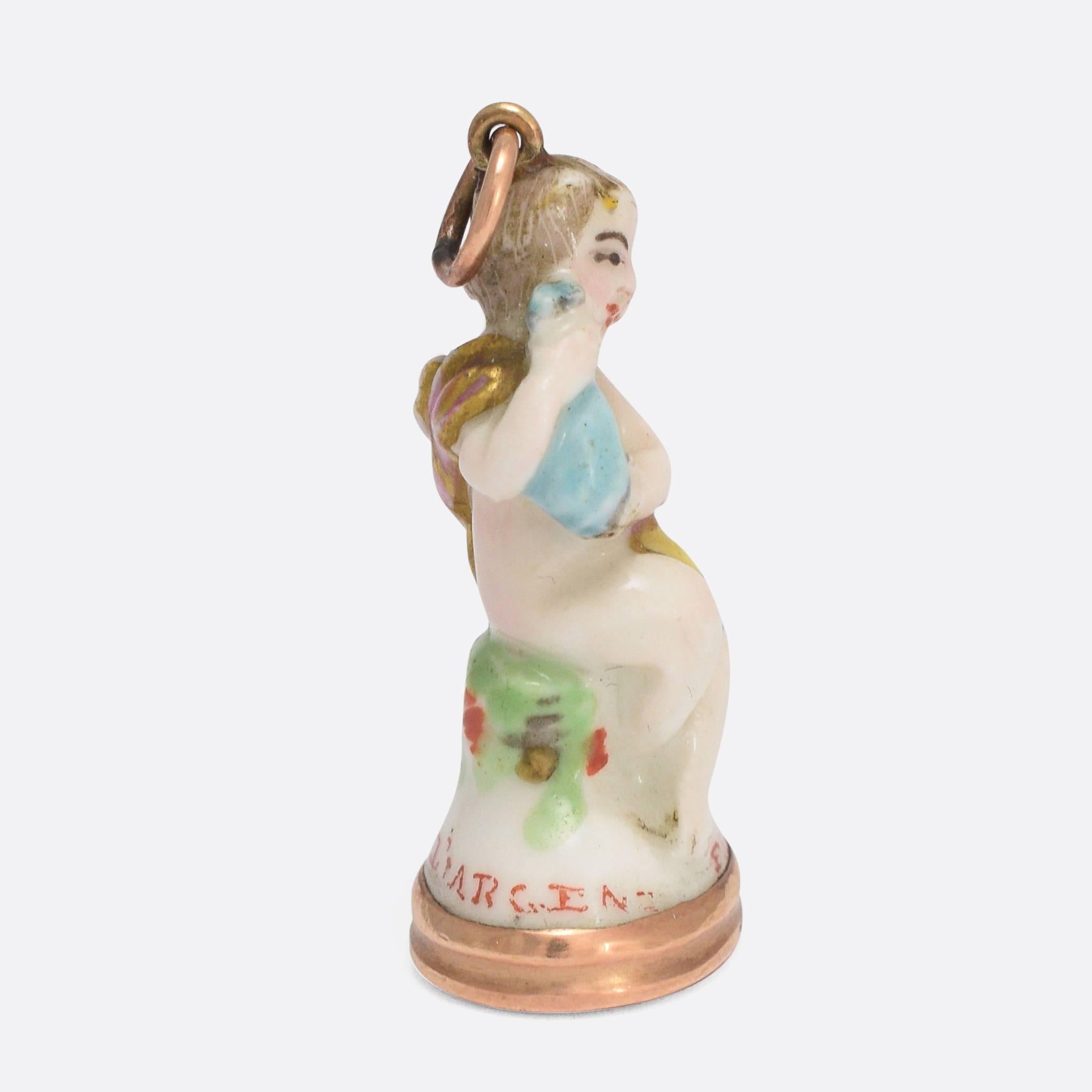 An original 18th Century porcelain Derby Chelsea period fob seal. This particular piece features Cupid holding a bottle and displays the pale colouring typical of the Chelsea factory. The gold bail and seal base are both present on this Georgian