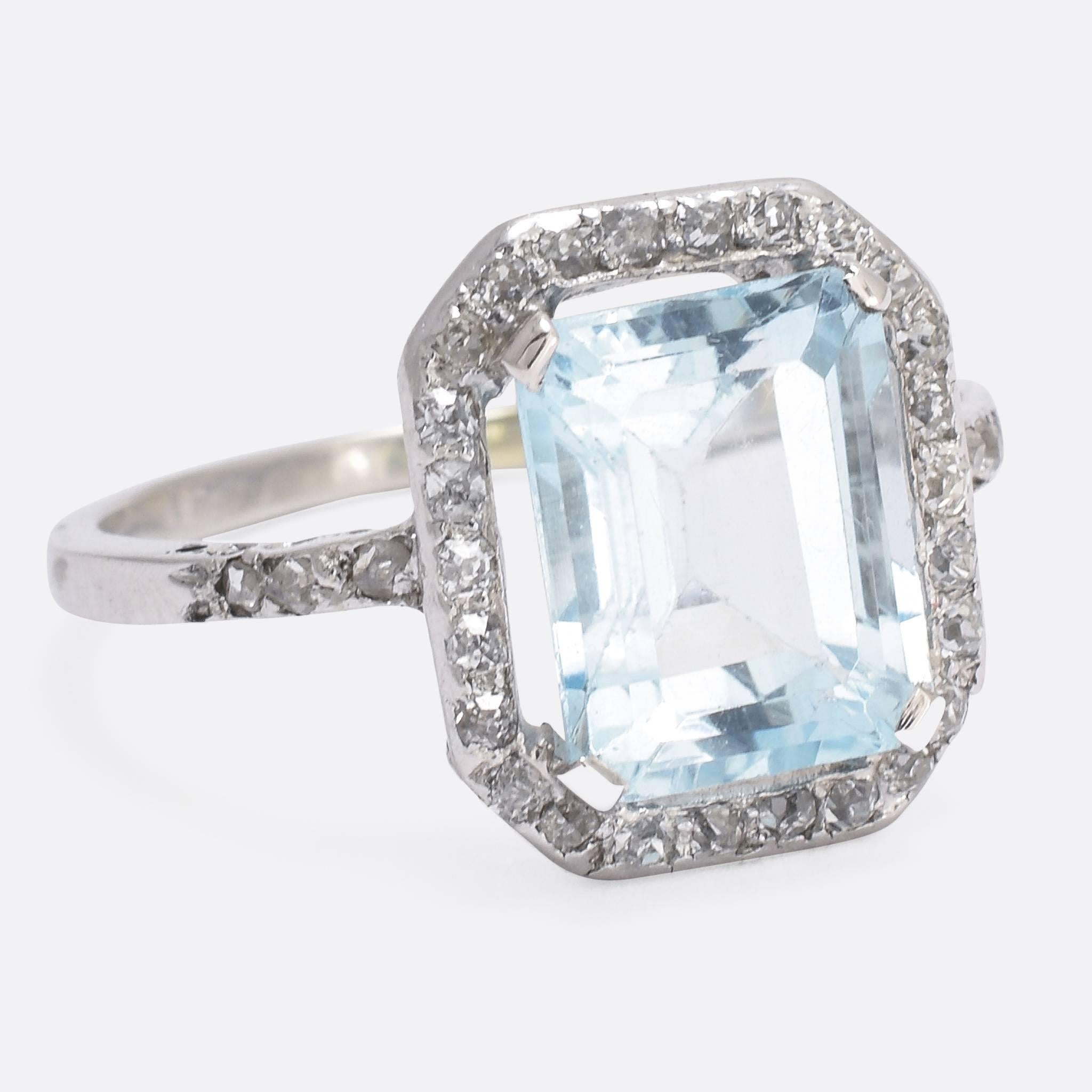 This beautiful antique engagement ring is set with a sublime 4 carat aquamarine, of excellent pale-blue colour, and a cluster of old cut diamonds. The ring itself is modelled in platinum throughout, and features a lovely openworked gallery and