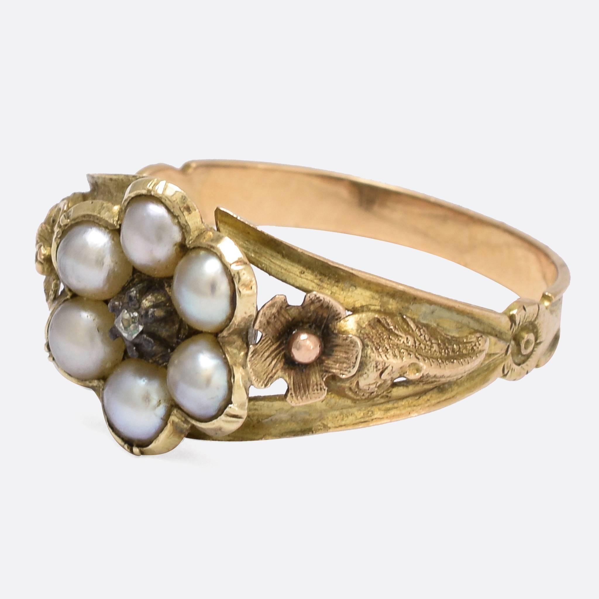 An adorable Georgian cluster ring set with six natural pearls around a rose cut diamond. The shoulders feature intricate applied flower and foliate goldwork, while the back of the head is home to a secret locket compartment. Modelled in 15k gold