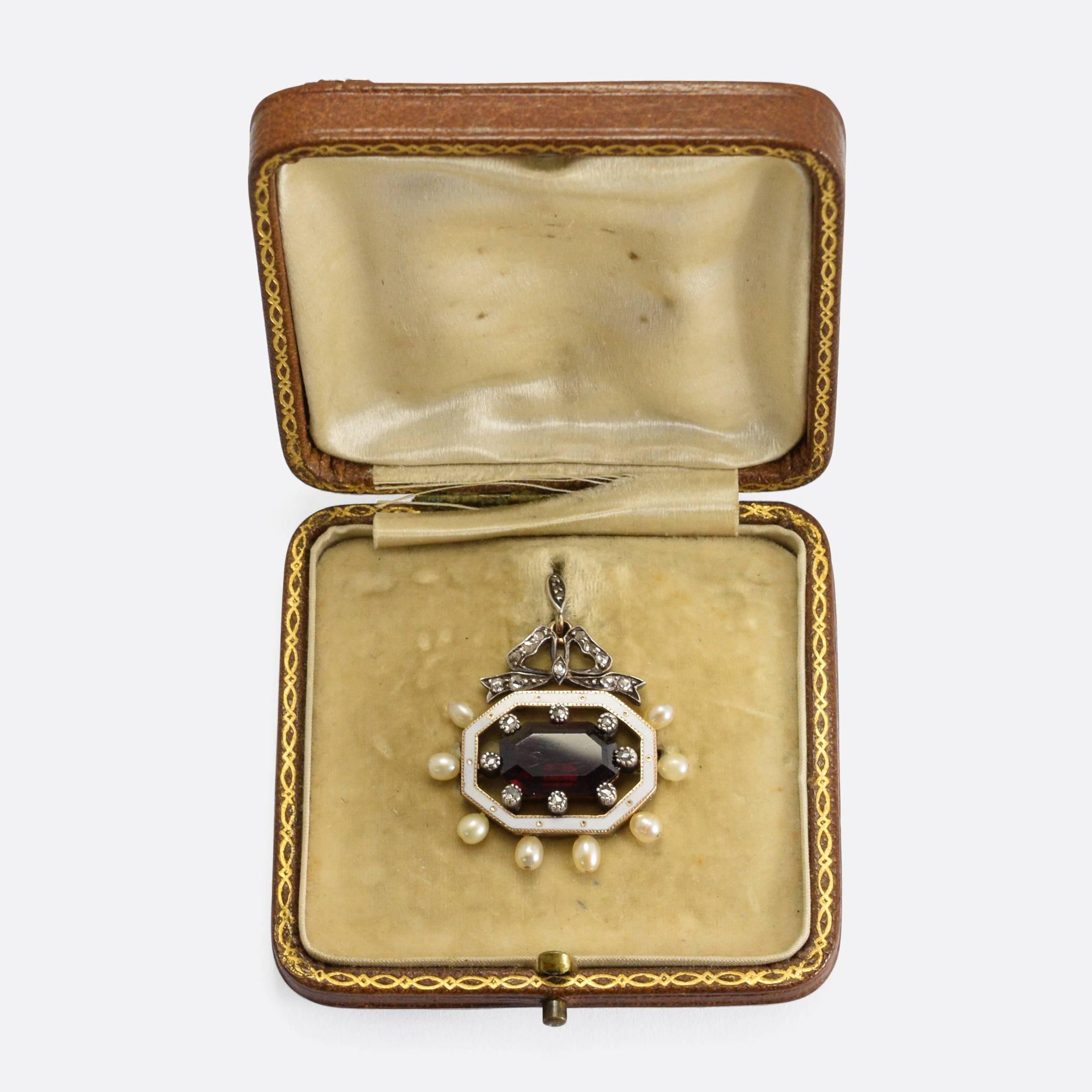 A stunning Victorian pendant in original fitted presentation box. The main stone is a gorgeous deep crimson garnet, surrounded by a halo of rose cut diamonds within an octagonal band of white enamel. Around the outside of the frame are set eight