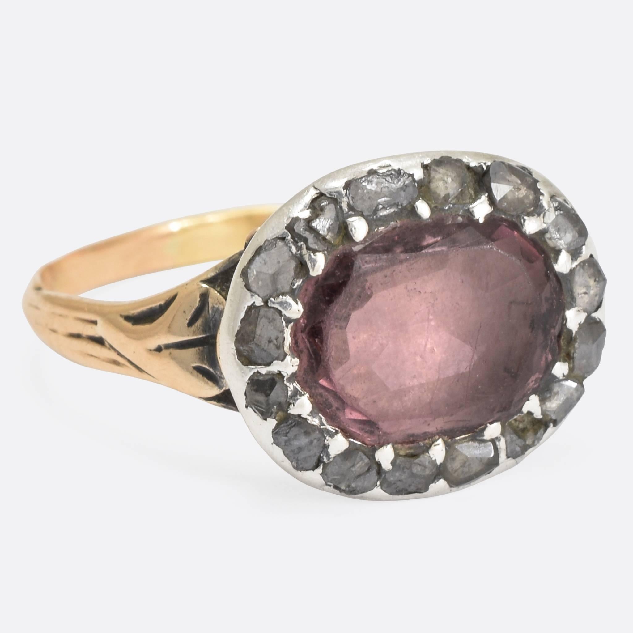 A fine quality Georgian cluster ring, the central faceted amethyst surrounded by a halo of rose cut diamonds all in silver settings. With lovely flowing foliate detail to the trifurcated shoulders. Ring size: 8.