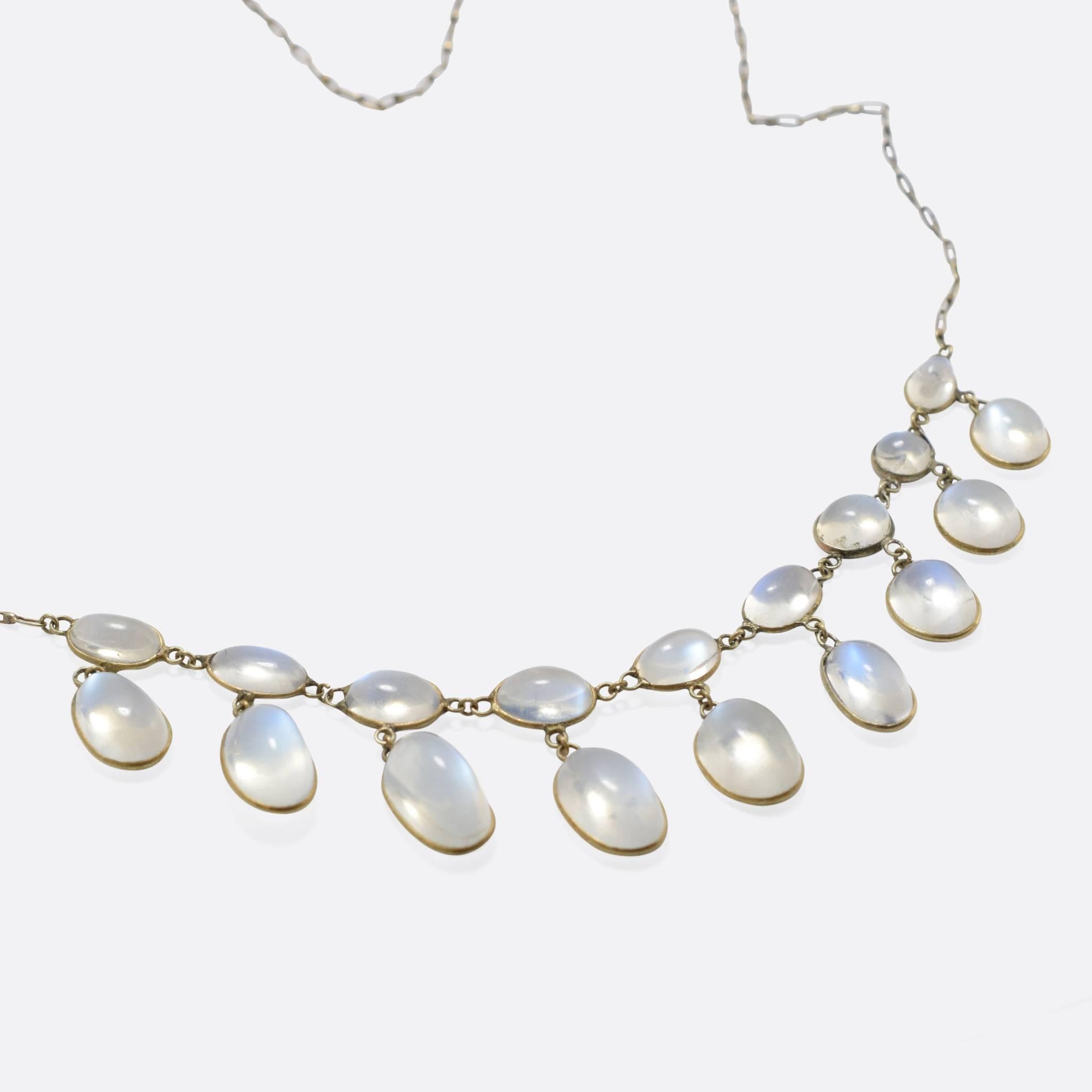 A magical blue moonstone festoon necklace, set with 18 individual cabochon stones in two tiers. The moonstones display excellent adularescence - the effect whereby they appear to glow brightly from within - and rest in 15k gold mounts on a long 21