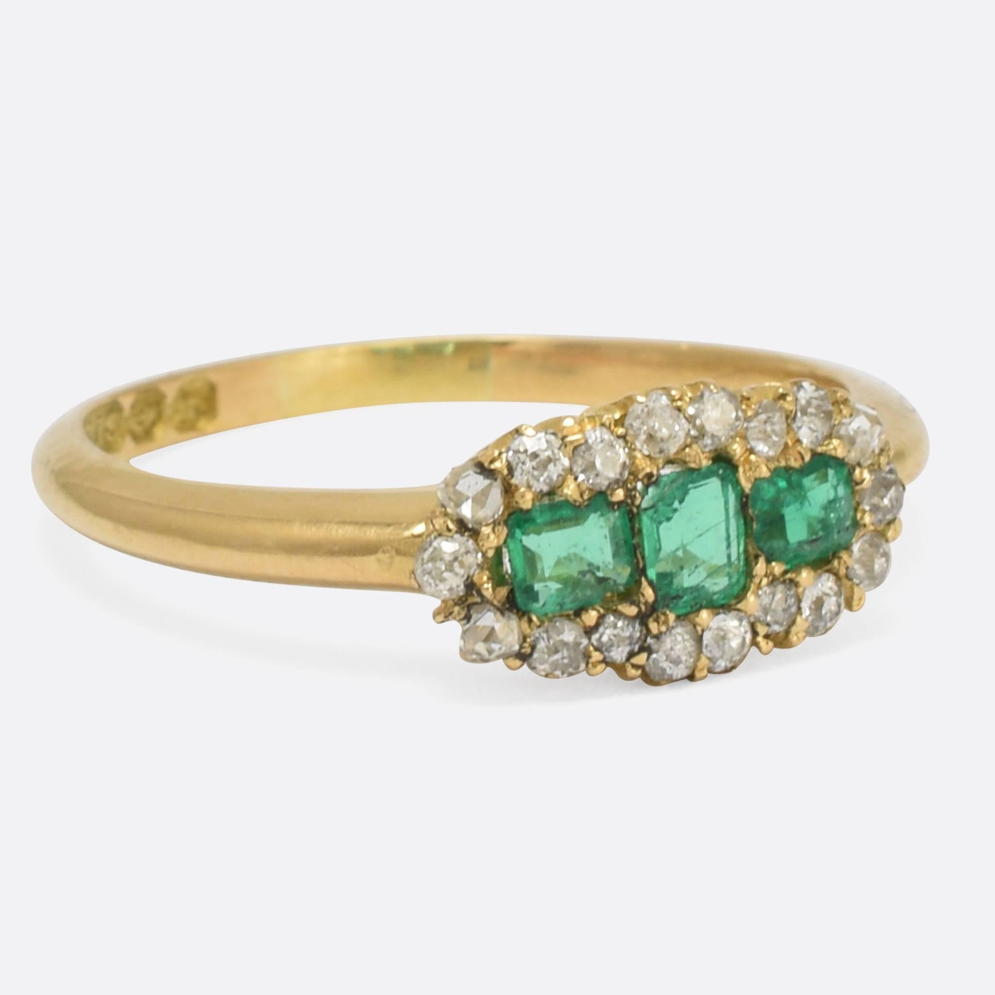 An adorable late Victorian emerald and diamond cluster ring. The three vibrant emeralds nestle between a cluster of old cut diamonds, all modelled in 18k gold. It dates to 1896, with clear Birmingham hallmarks to the inner band. Ring size: 7.75.