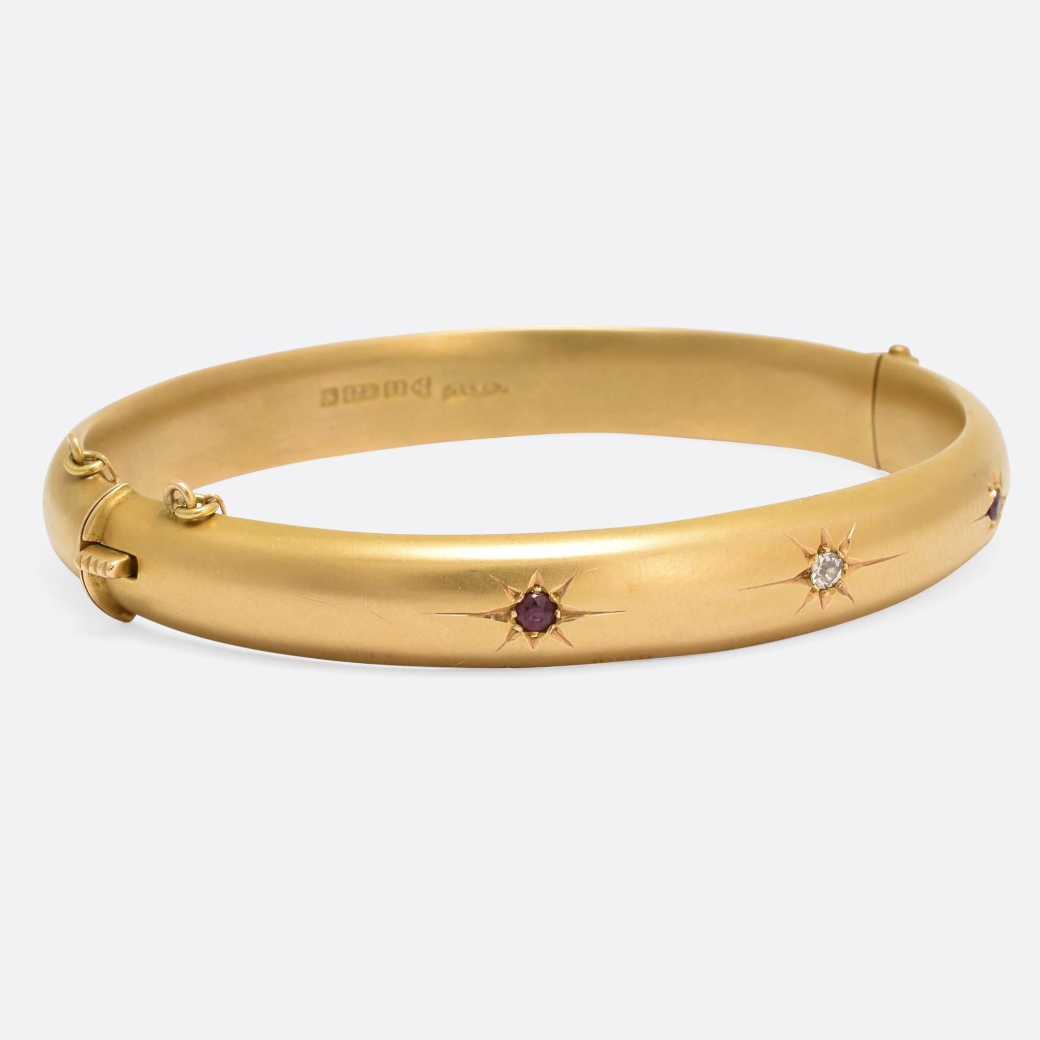 A stylish, but minimalist, antique bangle modelled in brushed 15k gold and set with two rubies and an old cut diamond. The piece is fully hallmarked, with the Chester date mark for 1907, and the gold has a lovely matte finish - the stones rest in
