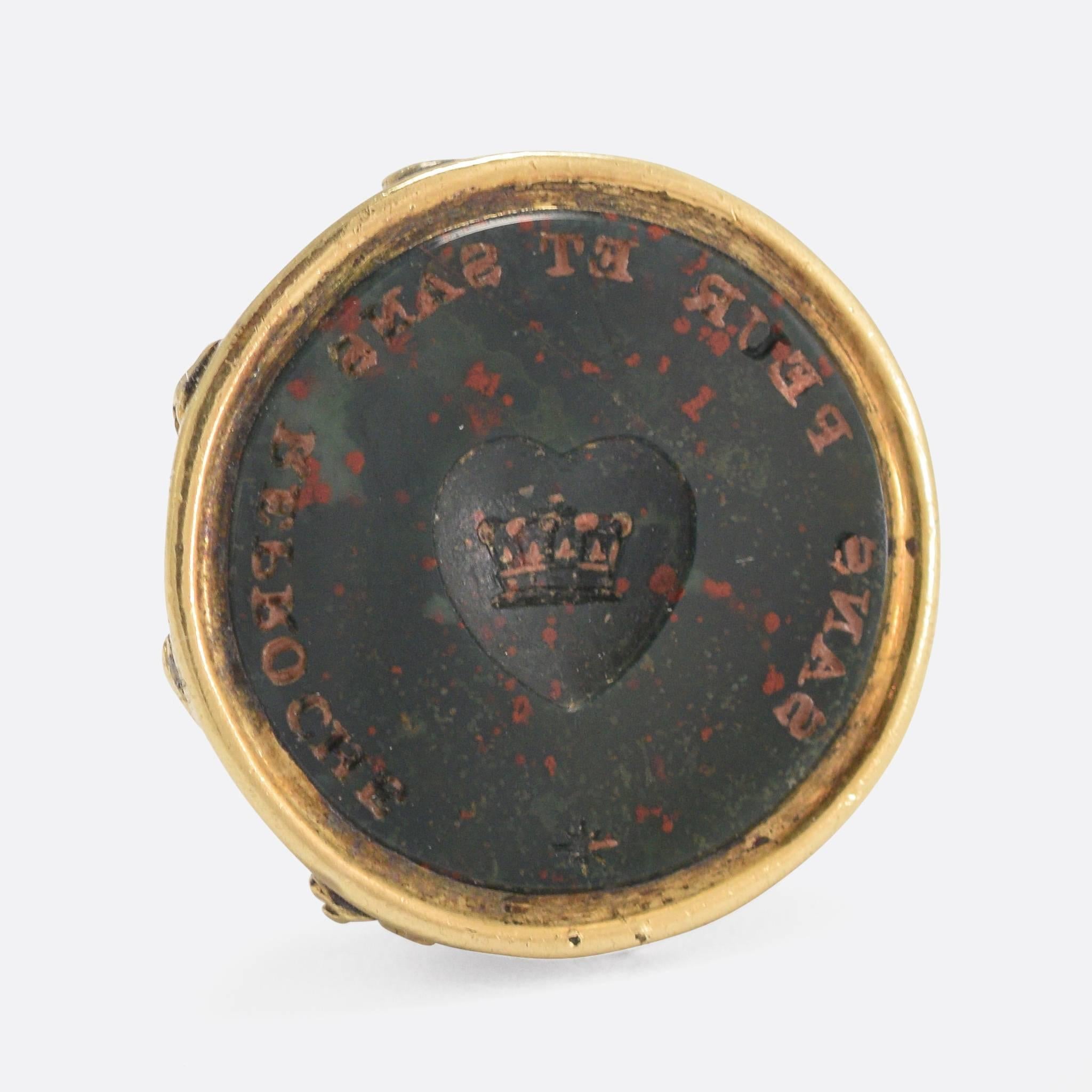 This late Georgian seal fob is set with a round bloodstone panel, hand carved with a crest and motto. In the middle is an intaglio heart (with a crown inside) and the words 