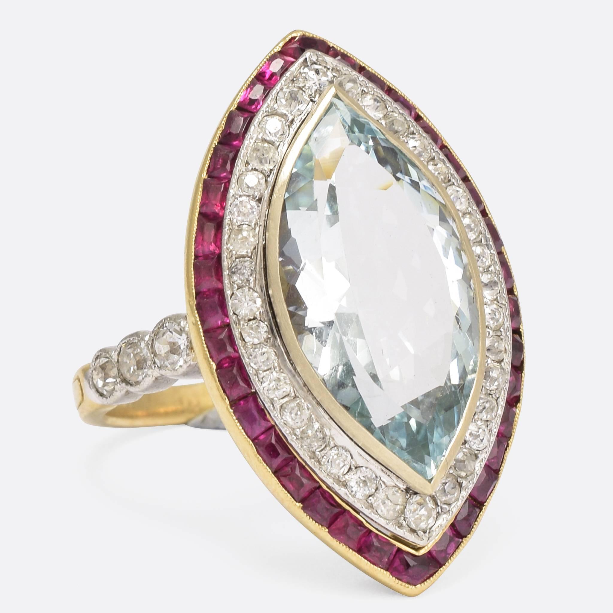 An astonishing Edwardian era marquise cluster ring, set with a central aquamarine framed by a double halo of diamonds and rubies. The quality is phenomenal, with wonderful pierced floral designs to the gallery, and three old cut diamond accents to