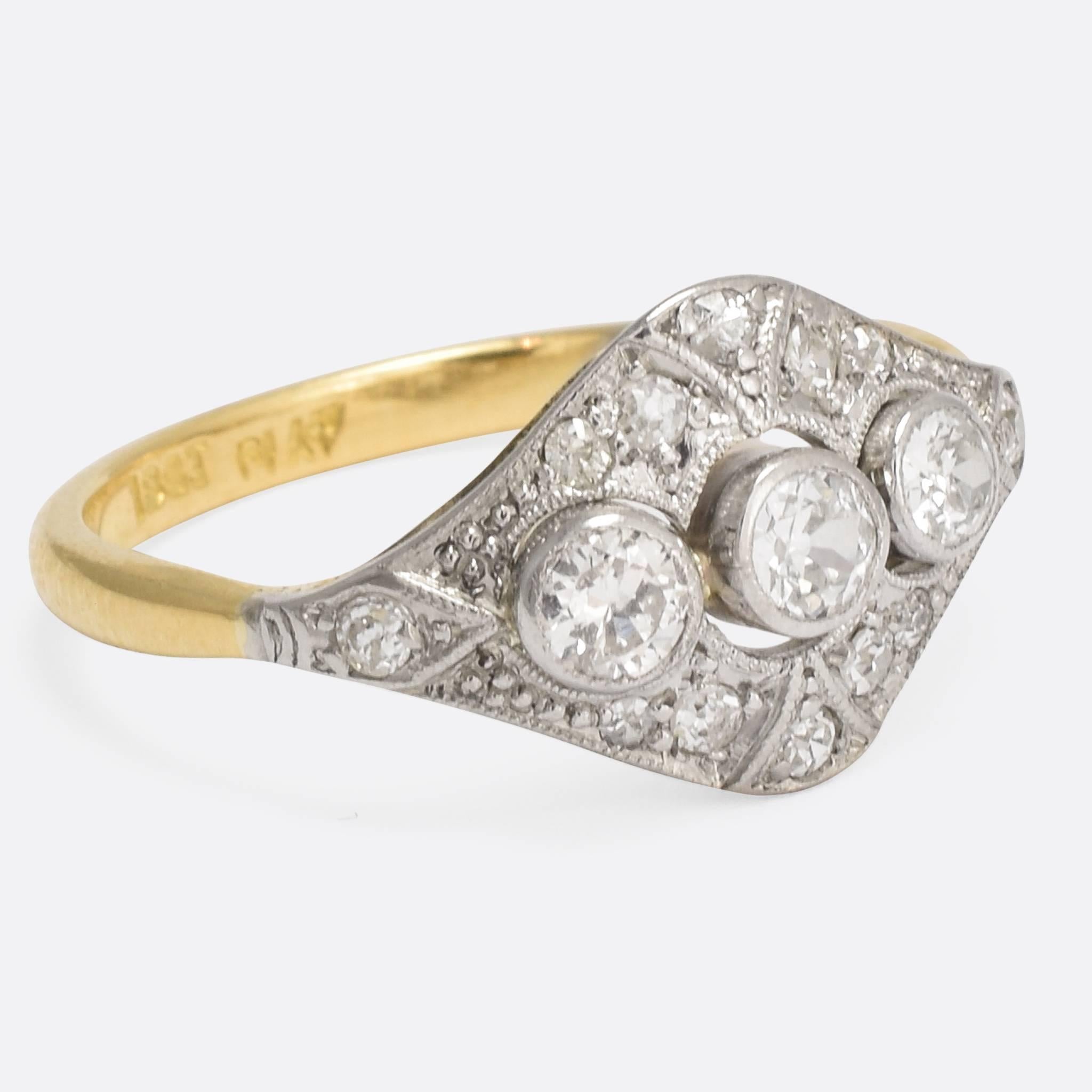 A wonderful diamond cluster ring, set with three old cut stones and and twelve eight-cuts. The head is tipped with platinum, with fine millegrain detailing, typically Deco in style, while the band is modelled in 18k gold with elegant pinched