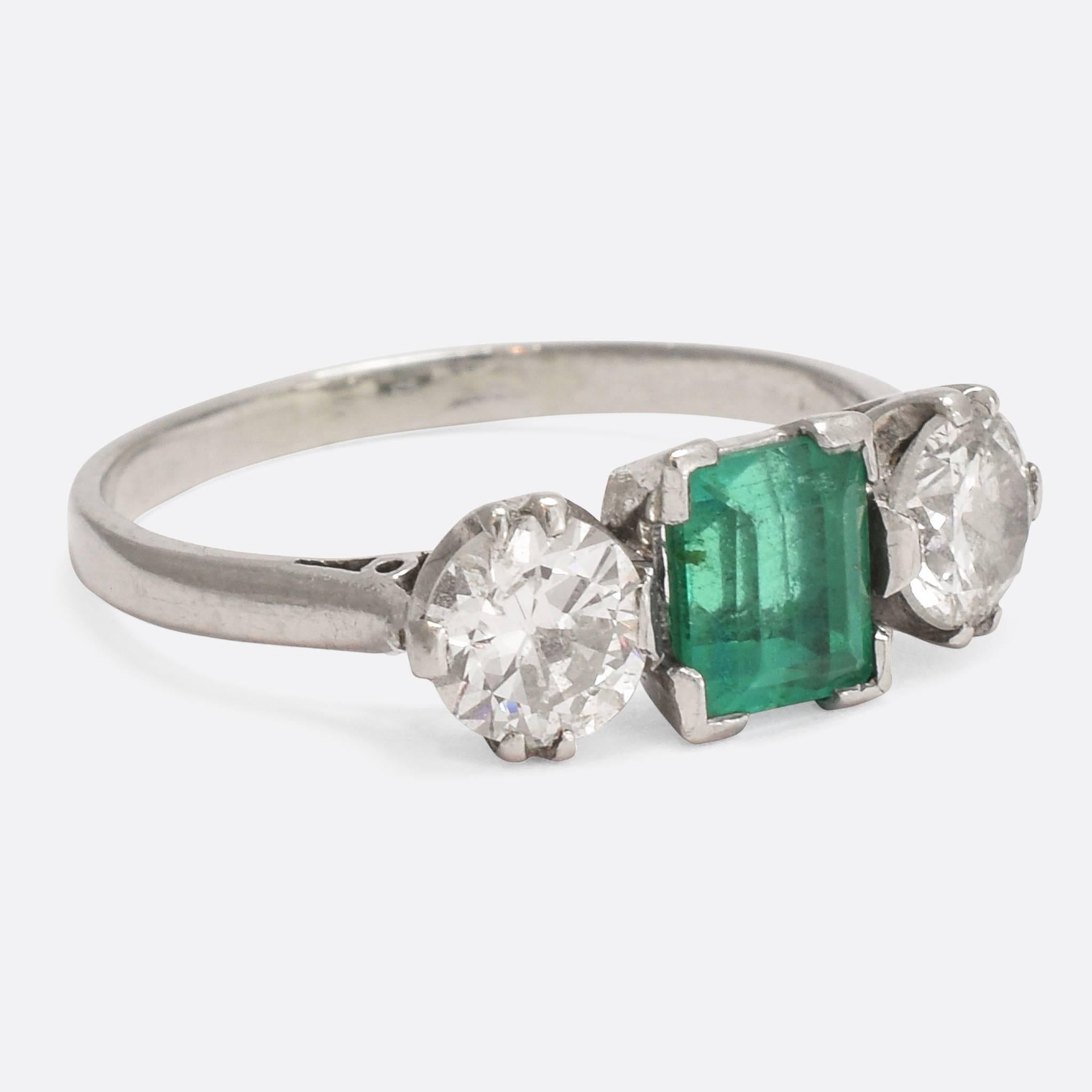 A mesmerising Art Deco era Emerald and Diamond trinity ring. The principal stone - held by four corner claws - displays excellent colour, and the two flanking transitional cut diamonds are bright and clean. An incredibly stylish 1920s take on the