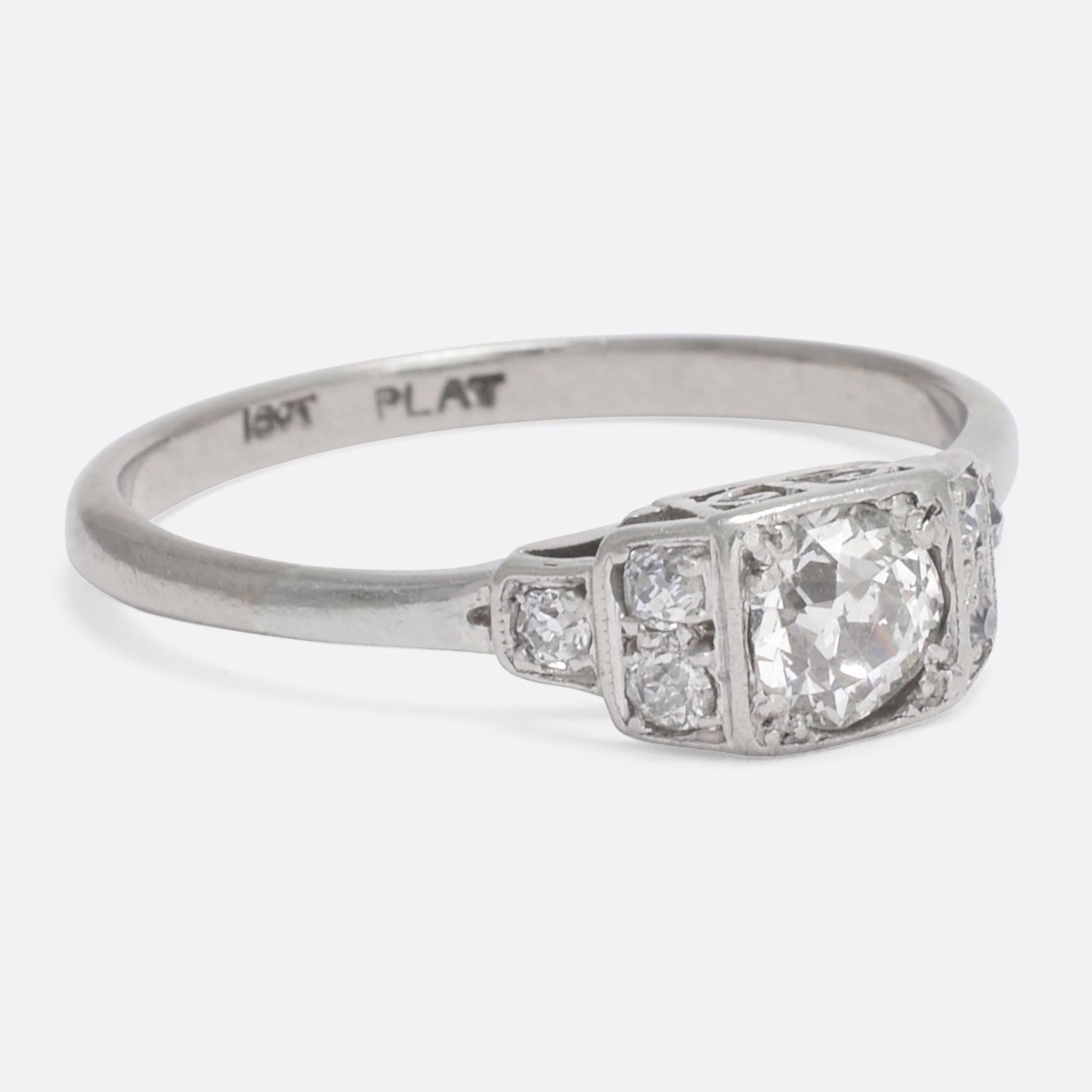 This superb Art Deco solitaire ring is set with a bright half carat old European cut diamond, with stepped shoulders home to six further old cut accents. Pretty scrolled motifs to the pierced gallery combine to form a heart, and also allow light in