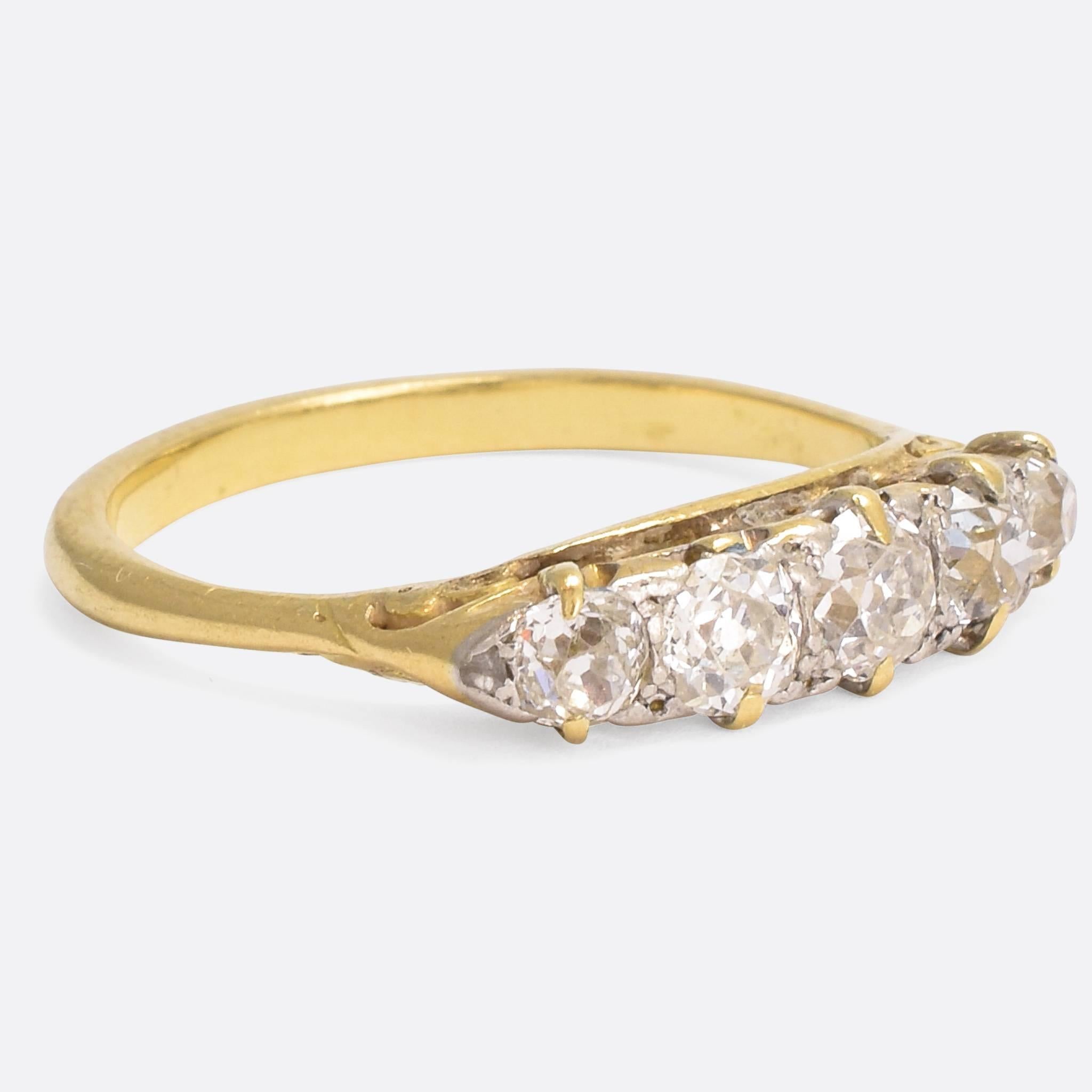 A beautiful Victorian 5-stone ring set with a full carat of old European cut diamonds. The ornate ring mount is very typical of its time, and features hand-chased sides with scrolled detailing and exaggerated claws. It's modelled in 18k gold, and