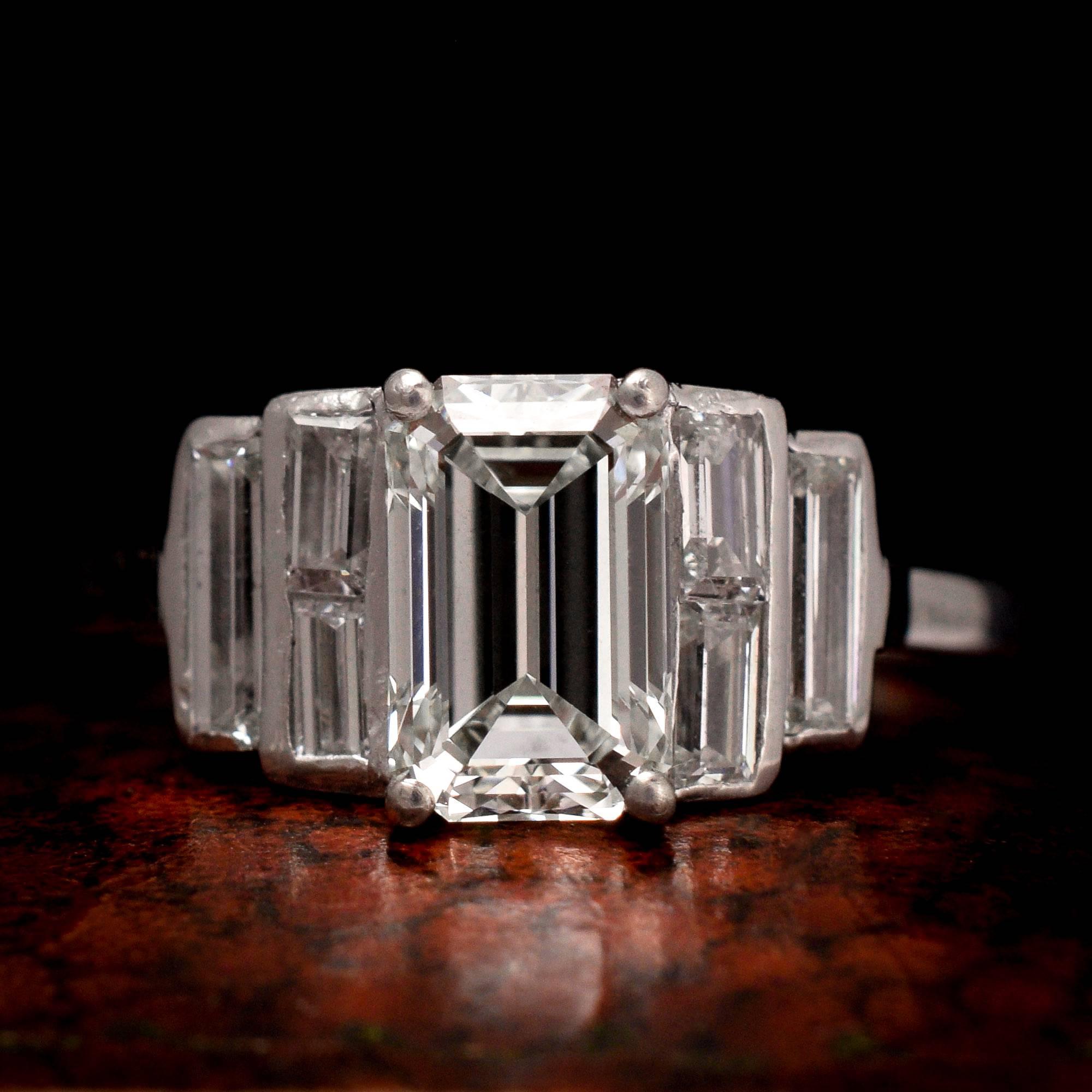 Art Deco, c.1925
An especially cool Art Deco engagement ring dating to c.1925, the main event being a 1.35 carat emerald cut diamond (with grading certificate stating K-VS1). The stepped shoulders are set with further baguette cut diamonds; the