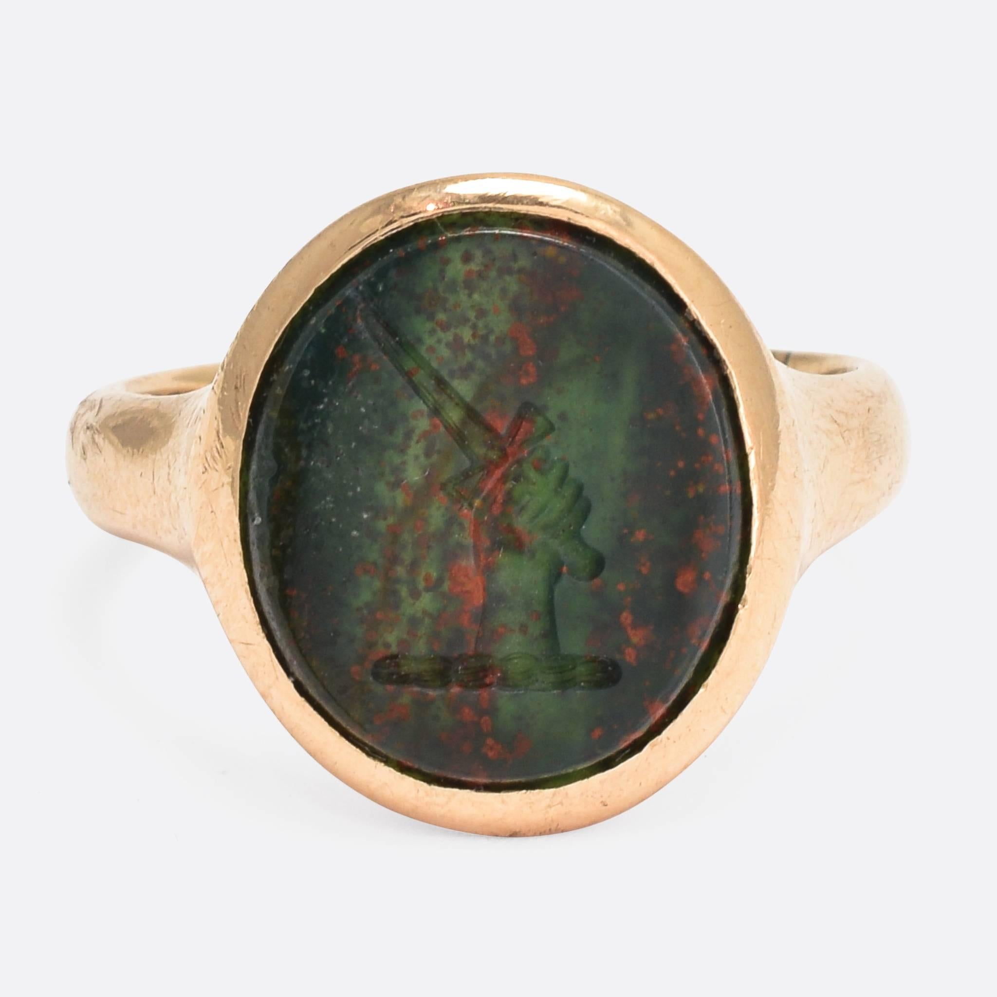 This cool antique signet ring features a heraldic intaglio crest, carved into an oval bloodstone panel. The crest is described by Faibairn as 