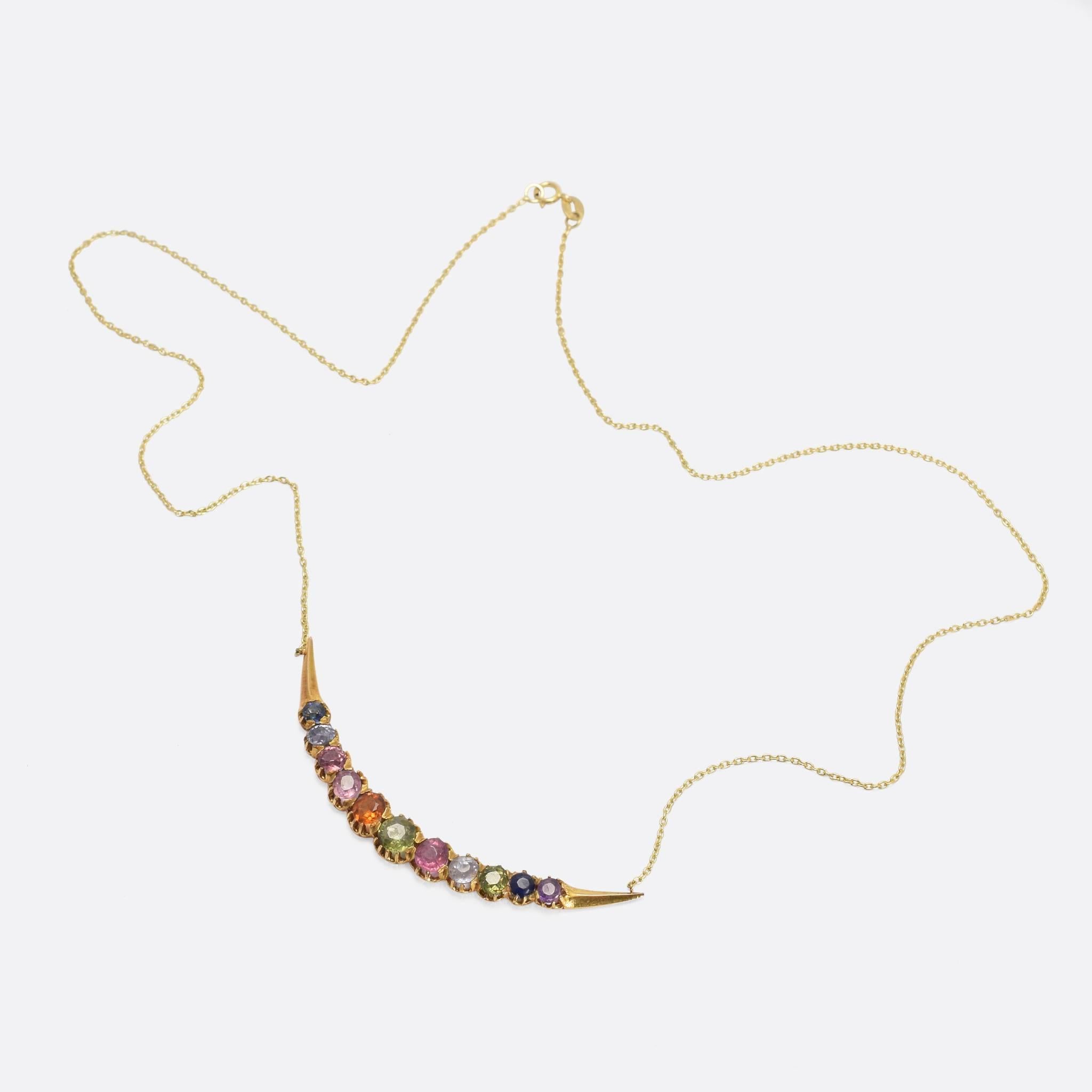 A gorgeous Victorian harlequin crescent necklace, set with a rainbow of coloured gemstones in scalloped claw settings. The stones include a central demantoid garnet, flanked by: blue and pink topaz, hessanite garnet, blue and pink sapphires, and