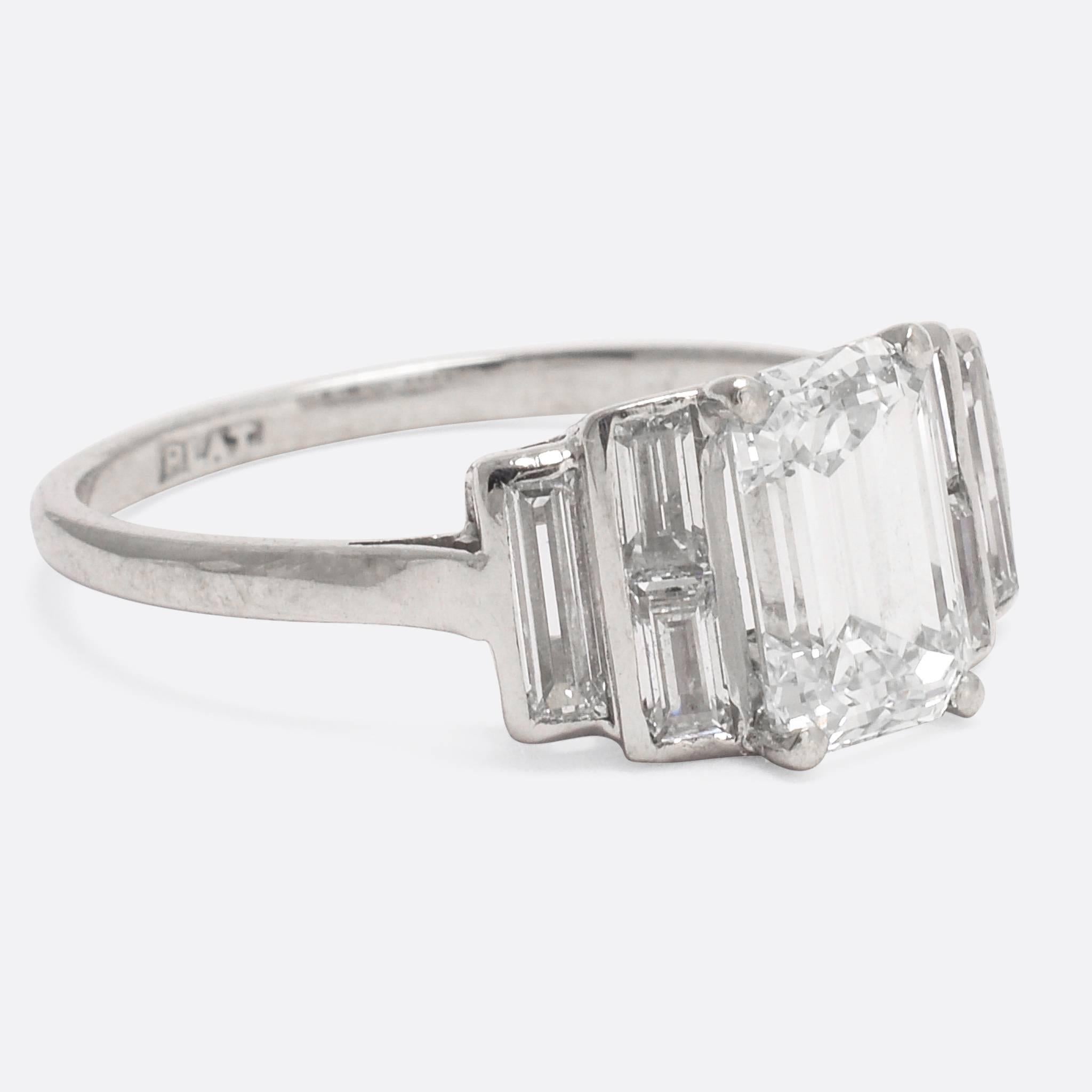 Art Deco, circa 1925
An especially cool Art Deco engagement ring dating to c.1925, the main event being a 1.35 carat emerald cut diamond (with grading certificate stating K-VS1). The stepped shoulders are set with further baguette cut diamonds; the