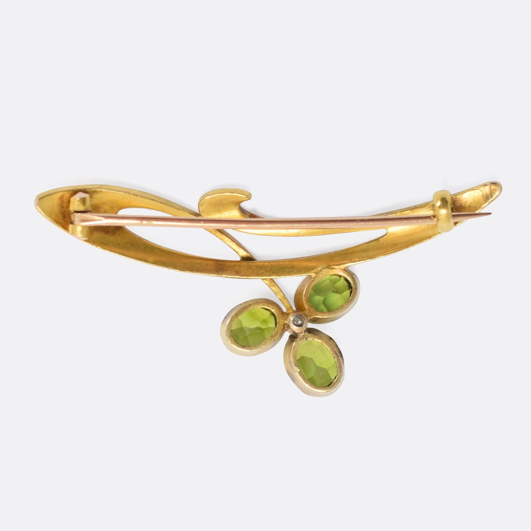 A superb antique Russian brooch, modelled in the Art Nouveau style. Worked in 14k (56 zolotnik) gold, the brooch is crafted as a stylised flower set with vibrant green garnets and a ruby cabochon - with elegant flowing goldwork typical of the era.