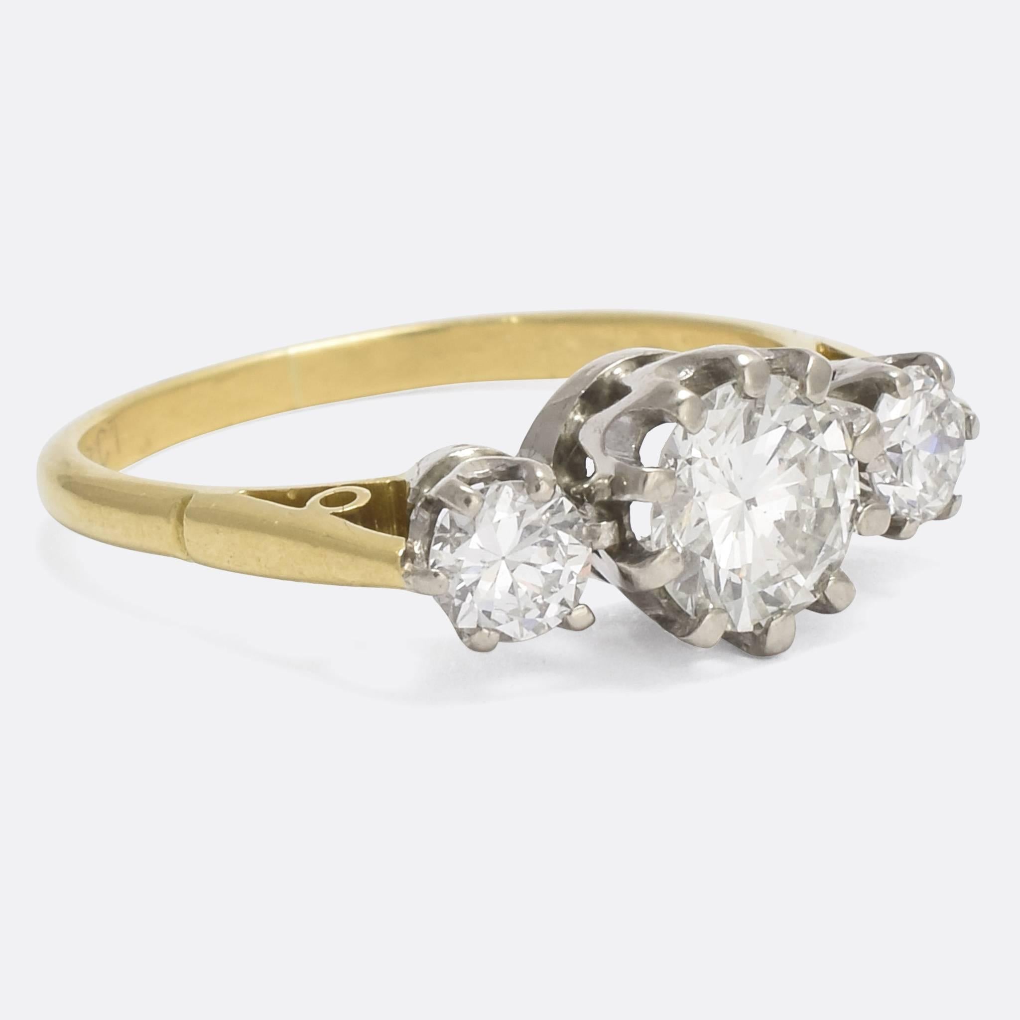 A spectacular 1930s diamond trilogy ring, set with a carat centre stone flanked by two quarter carat stones. Modelled in 18k yellow gold with platinum claw mounts, the diamonds are clean and bright. It would make the perfect vintage engagement