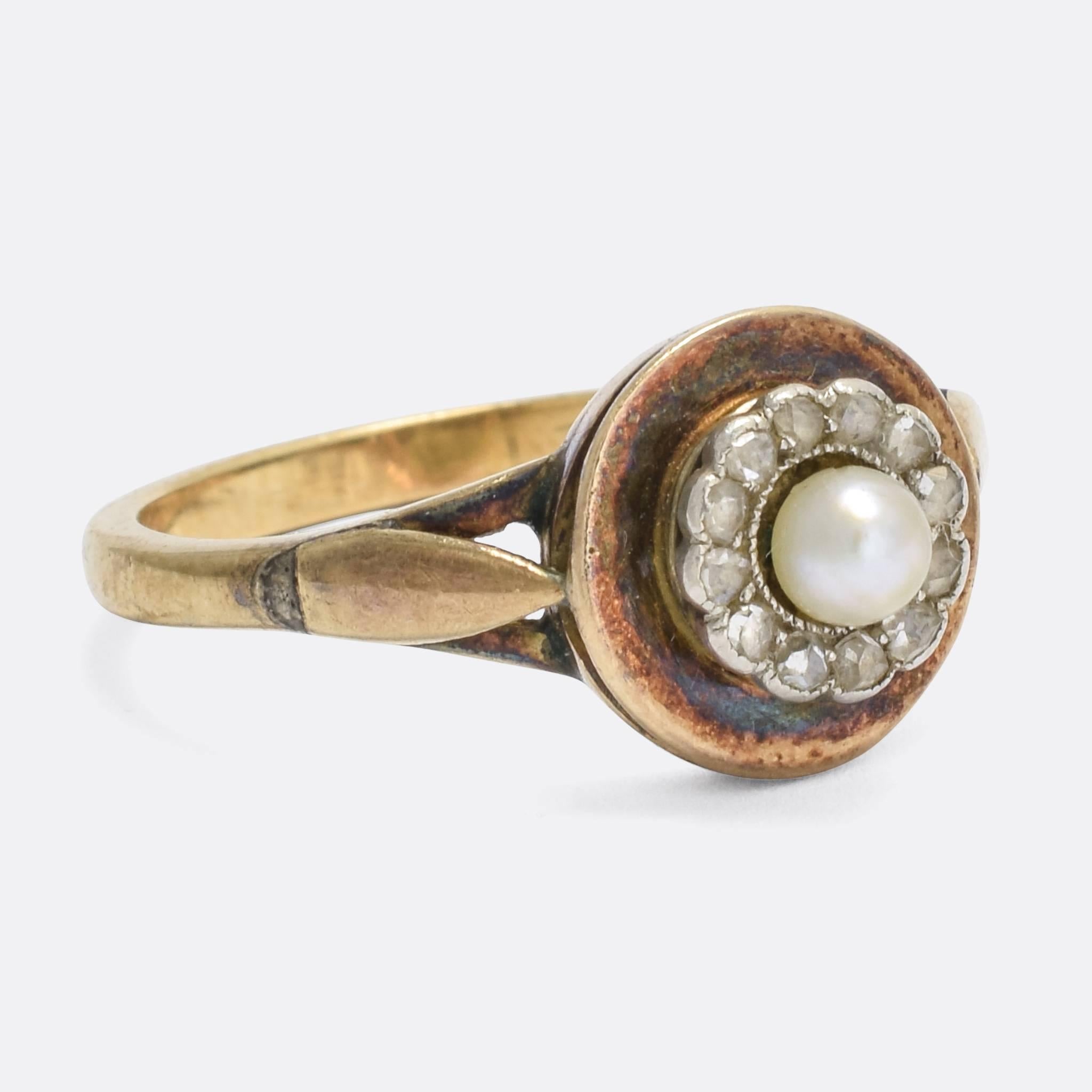 An unusual antique cluster ring, set with a halo of rose cut diamonds around a central natural pearl. This cluster sits raised above a larger gold disc, to create a double halo effect. The stones are set in platinum, with fine millegrain detailing,