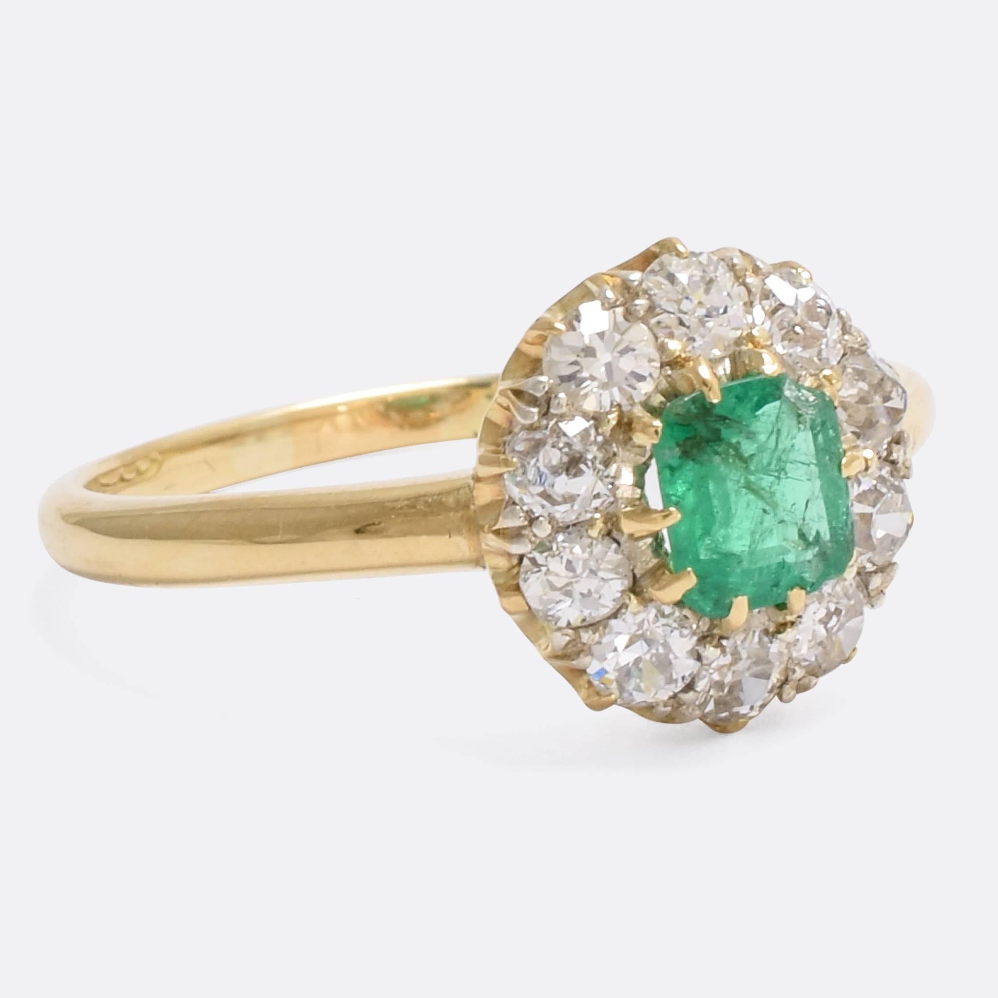A cool Edwardian period emerald and diamond round cluster ring. The central stone is bursting with colour, resting within a .70ct cluster of bright old cut diamonds. The ring is modelled in 15 karat gold, and the diamonds are set in platinum-tipped