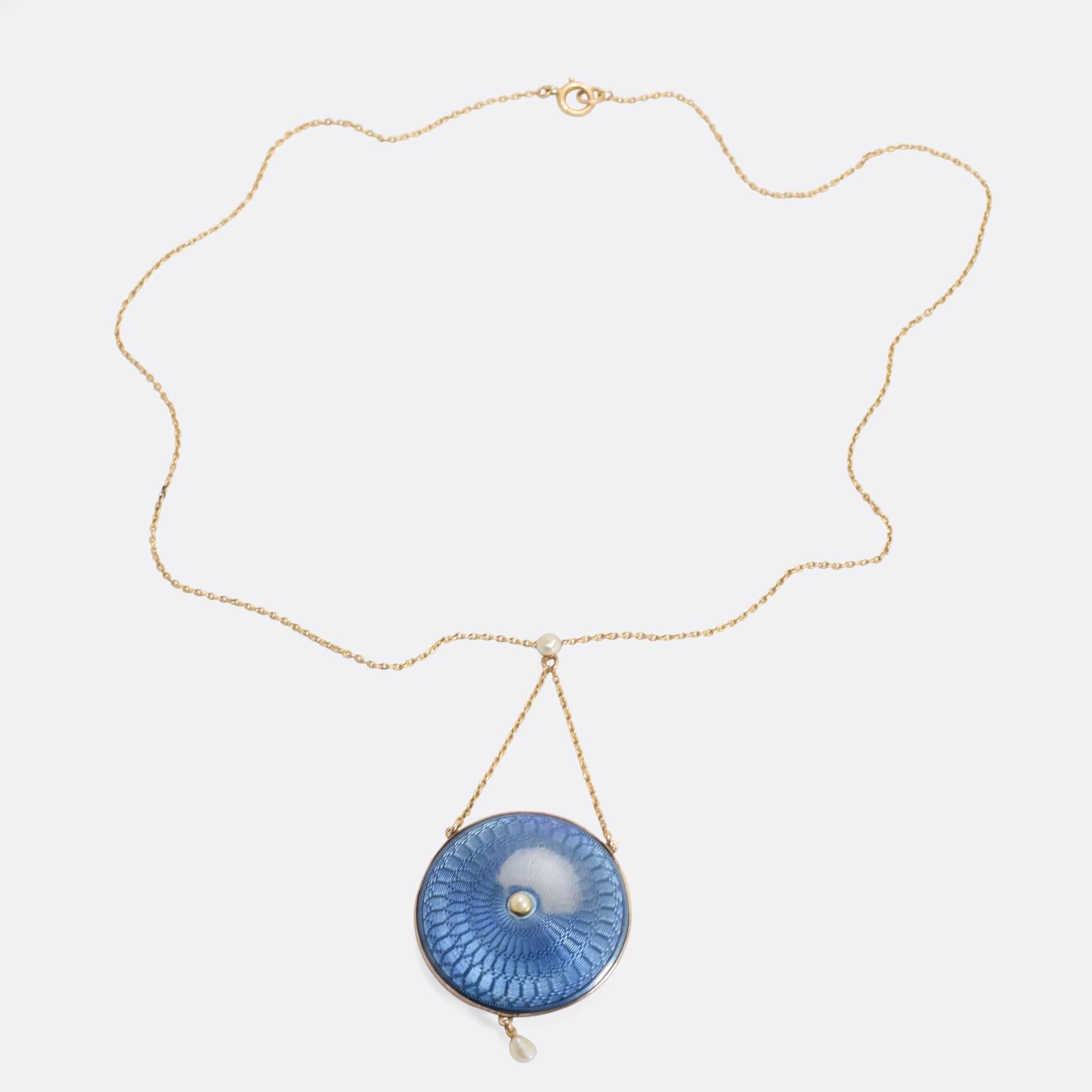 A stunning Edwardian round locket, finished in beautiful powderblue guilloché enamel. It hangs from a fine gold chain, with a pearl at the poin it crosses, another pearl in the middle of the locket, and a third (this one a baroque pearl) dangles