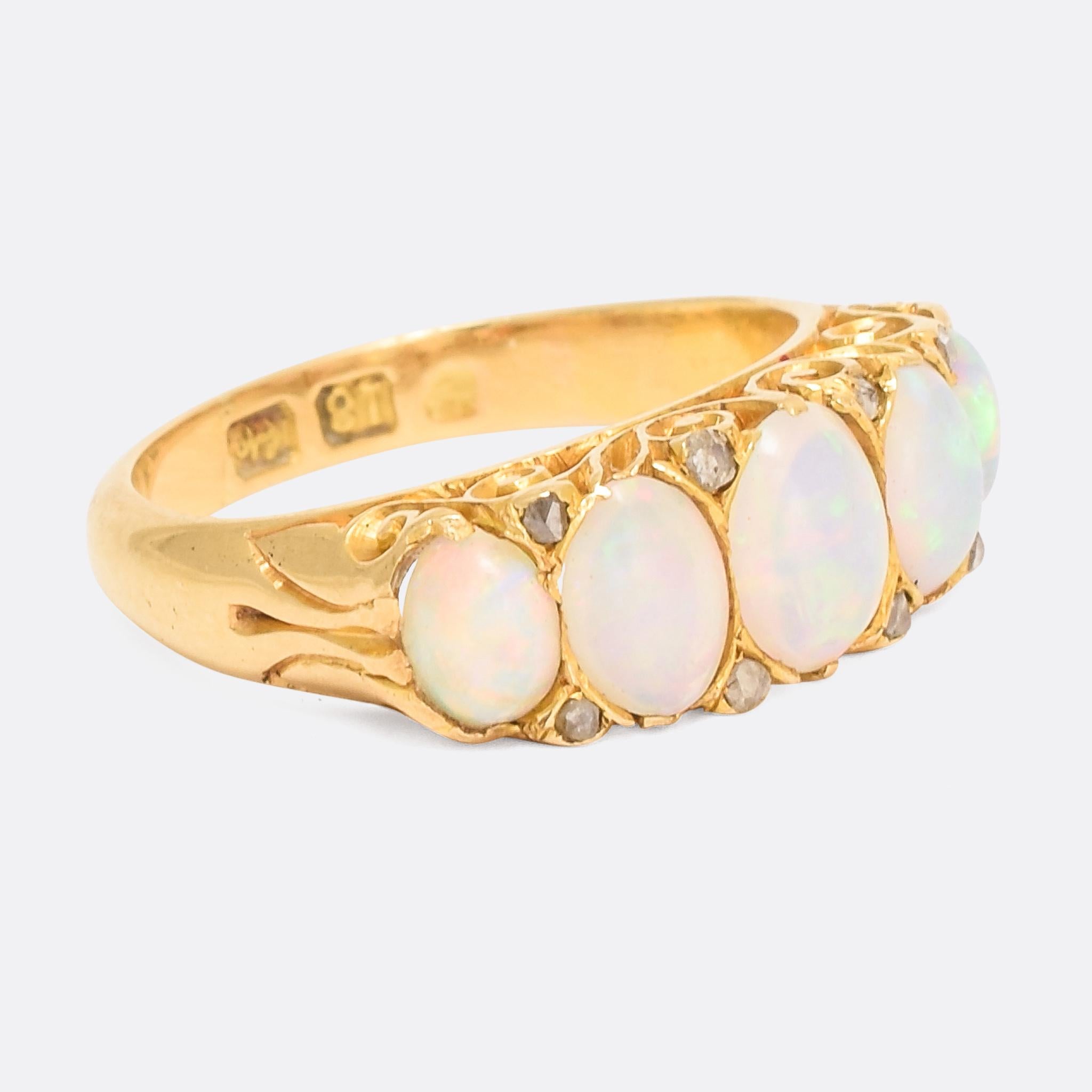 A particularly lovely Victorian ring. Set with five vibrant opal cabochons, the gallery features deeply chased scrollwork, and the in gaps between the oval stones are set rose cut diamond points. It's modelled in 18 karat yellow gold which has