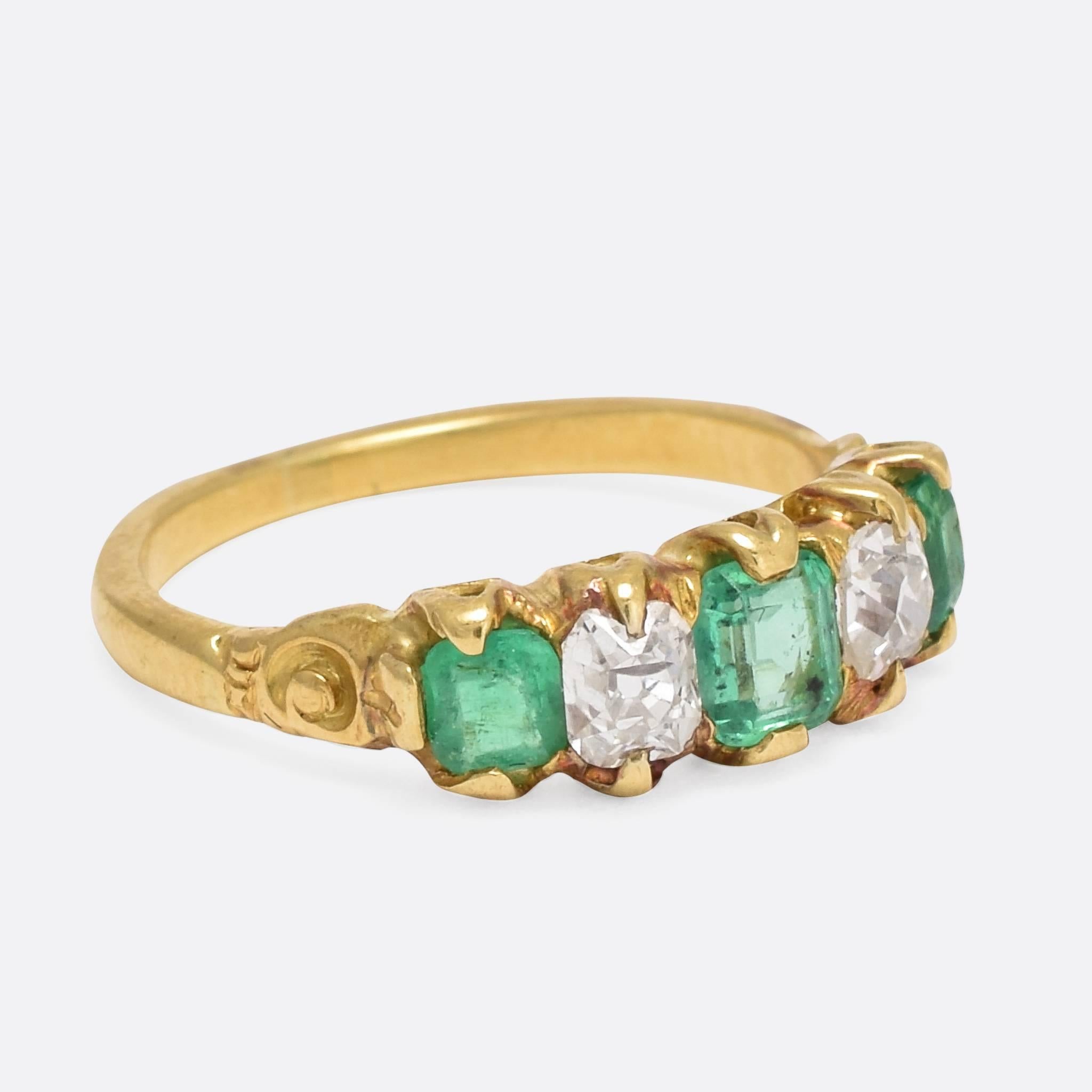 This splendid antique five-stone ring is set with three vibrant emeralds and two old mine cut diamonds. Modelled in rich 18ct yellow gold, the head displays pretty galleried sides, allowing in light behind the stones - while the shoulders feature