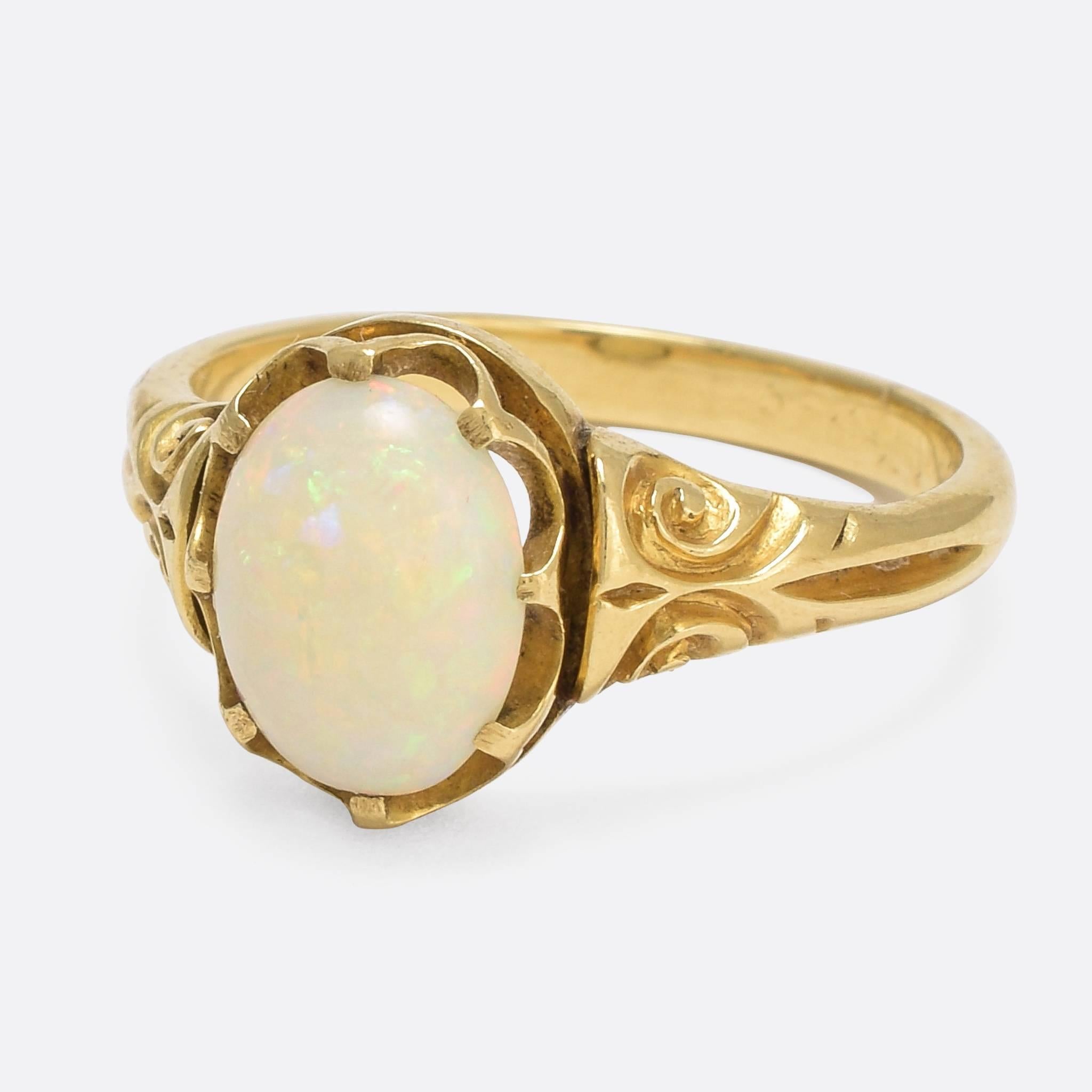 A beautiful antique single stone ring, set with a striking 1.1 carat opal cabochon. The stone displays excellent colour, with flashes of blues, greens, orange, pink and purple - while the 18k gold setting features pretty hand-chased scrolling to the