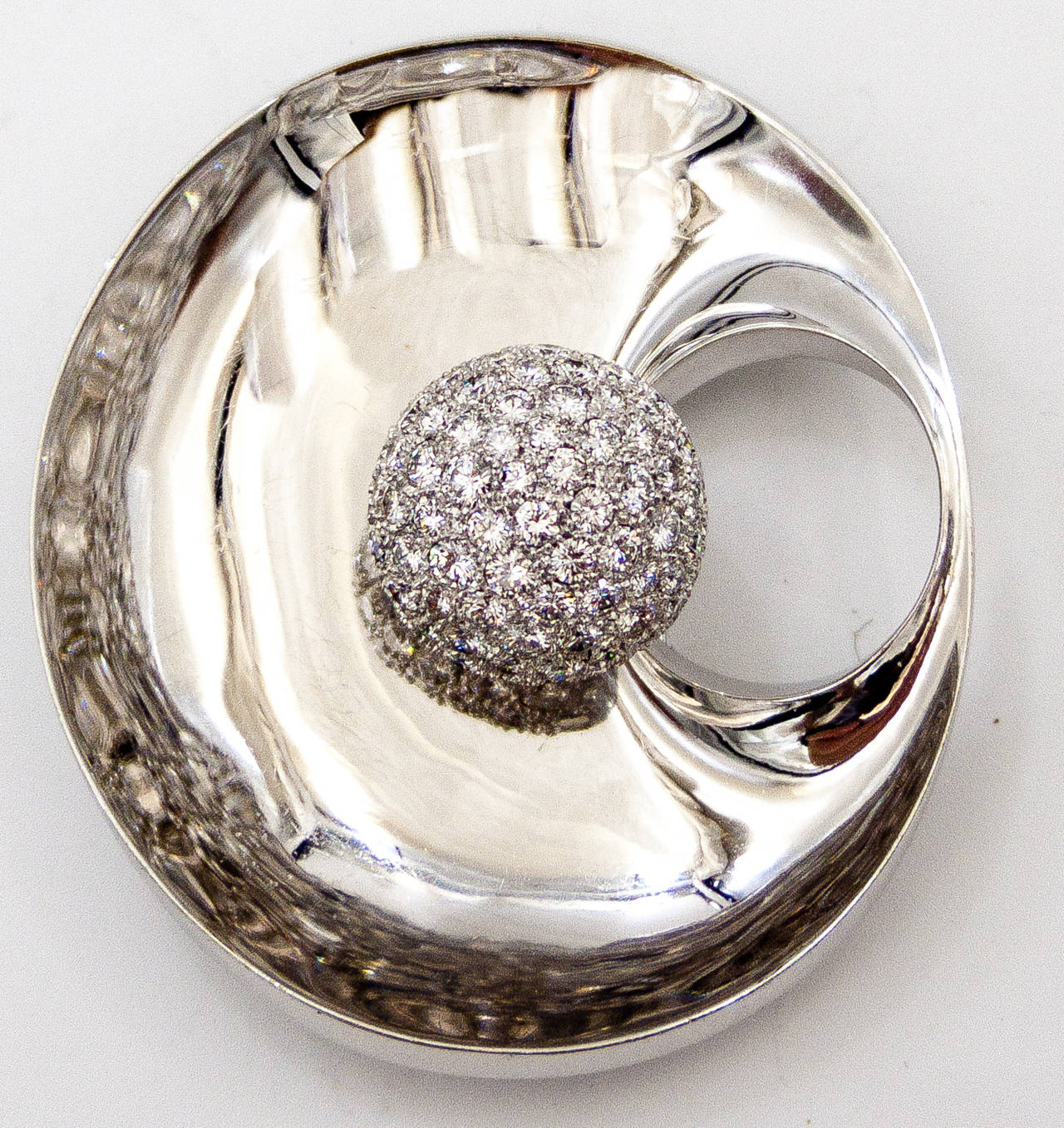 An intriguing suite by Piaget with beautifully set pave diamond balls both on the ears and floating on a pin of smoothly polished, mirror- finish 18karat white gold.   The pin has a wonderful, saucerlike dip towards the center, causing reflections