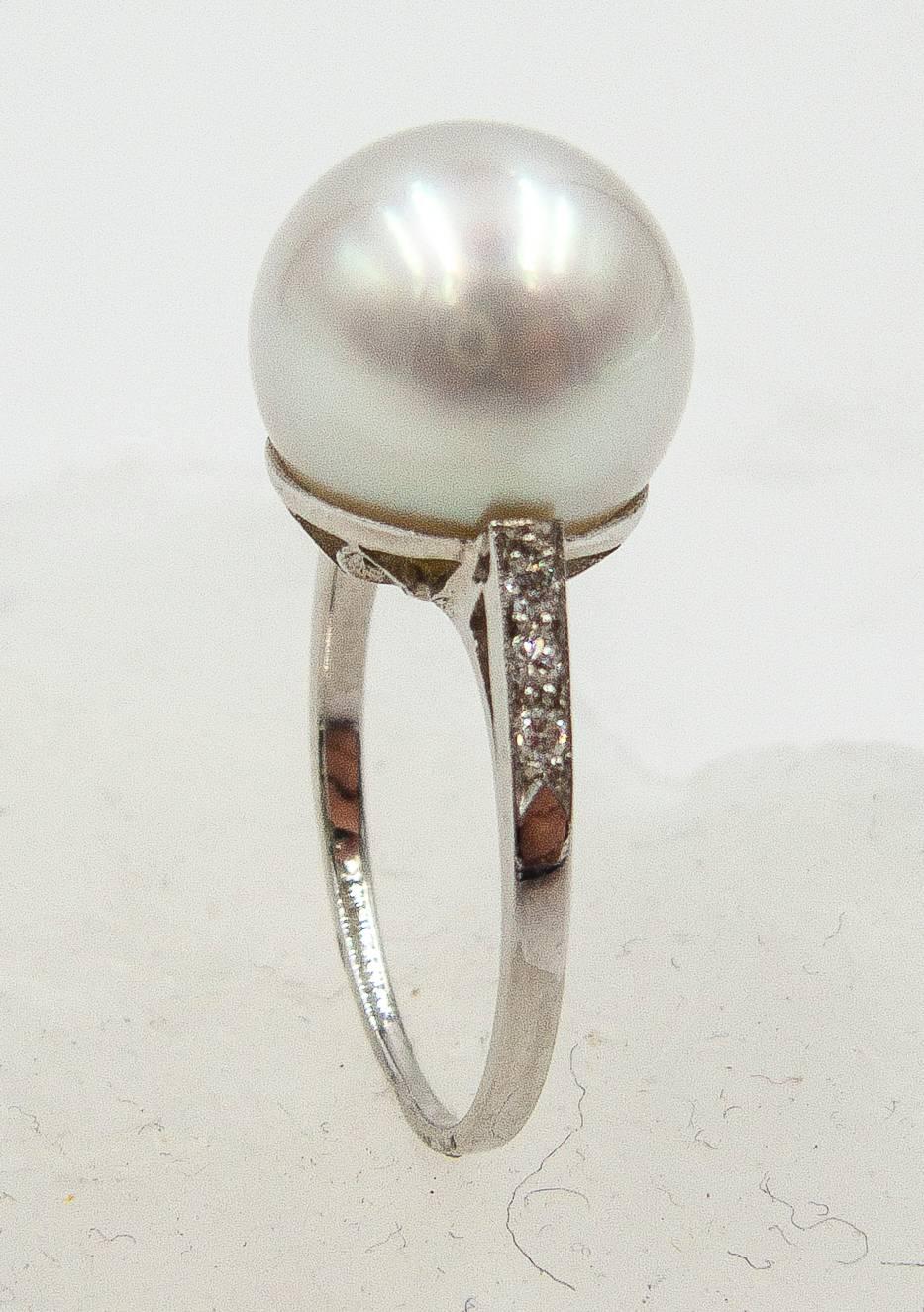 Classic elegance in a pearl and diamond ring.   A  full,softly lustrous white South Sea pearl measuring 11.5 millimeters sits atop a handmade platinum mount, the shoulders accented with petite full cut diamonds.   This is a ring that is timeless and
