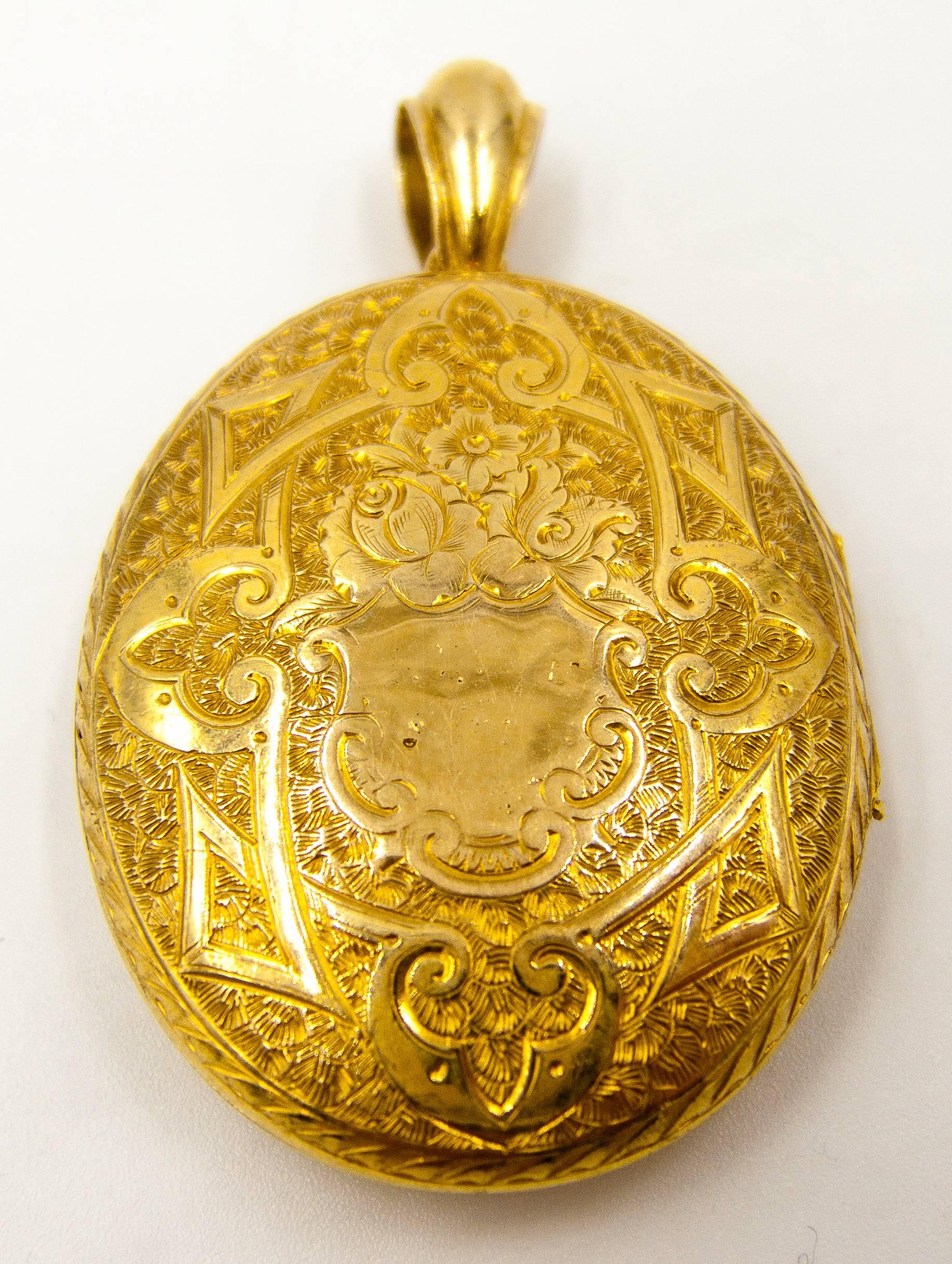 A delightfully ornate locket, heavily curlicued and engraved on front and verso.   One side sports a stylized lotus blossom, and the other side has a small shield shape onto which initials can be engraved.  15 karat gold, so typical of jewels from