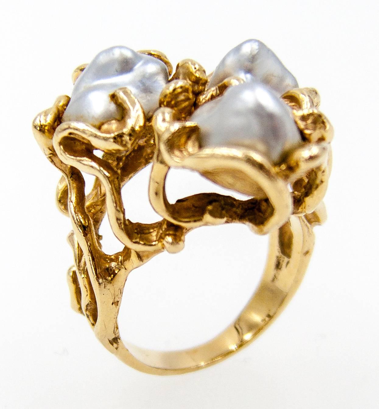    A flashback to the 60's, this ring is a fun example of studio created jewels of the decade.   Three freshwater pearls, probably sourced from the Mississippi River, are caged within asymmetrical fronds of 14 karat yellow gold.   The ring is size 6