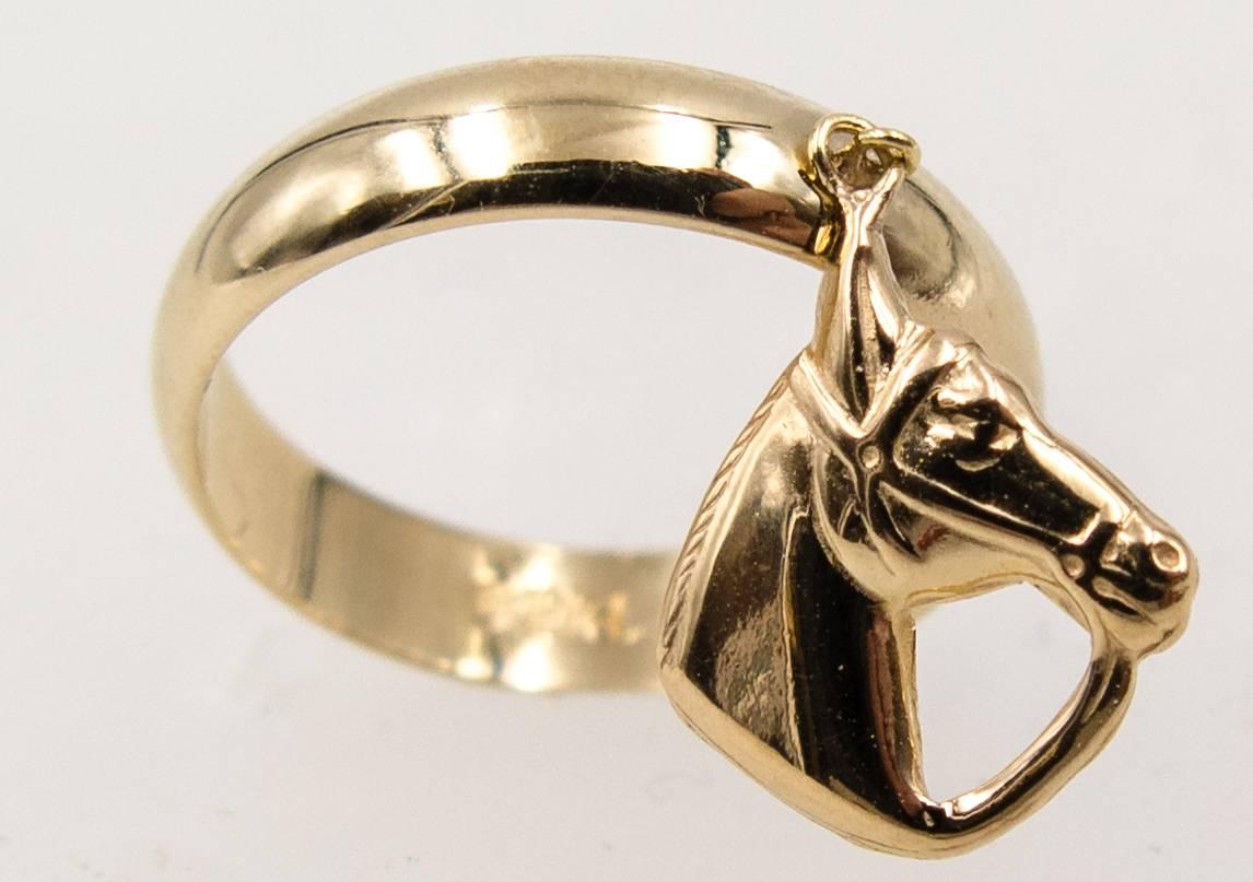 For a horse of a different color, consider this unusual little charm ring if you own a horse - or just like going to the races.  A size 6,  4 mm wide 14 karat gold highly polished domed band supports a movable horse head charm that swings around as