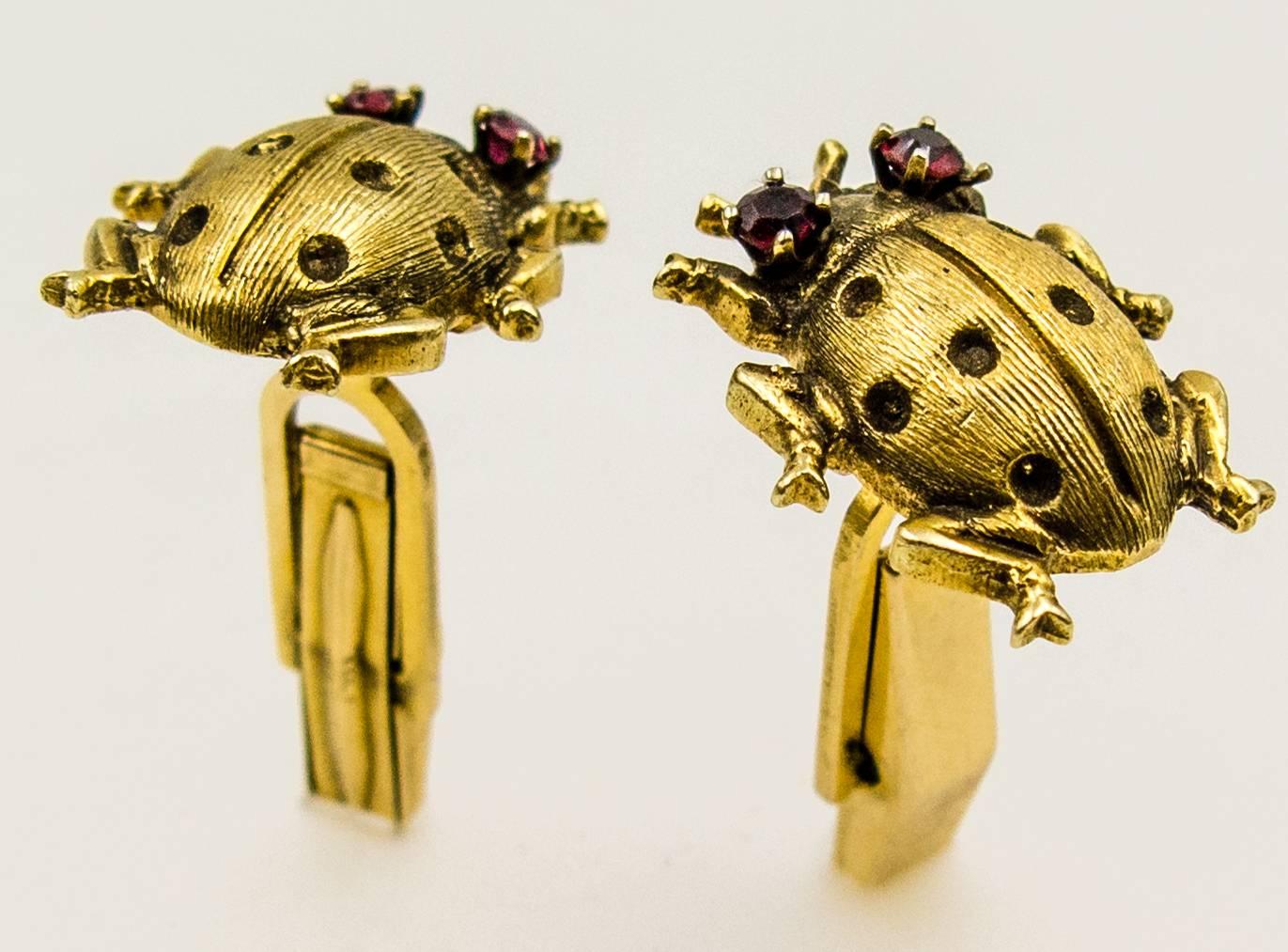 Charming 14 karat gold ladybug cufflinks with round and sparkling red garnet eyes will be a conversation piece in any shirt cuff.  The domed bodies are accented with straight engraved lines and dotted depressions, and its footpads are poised for