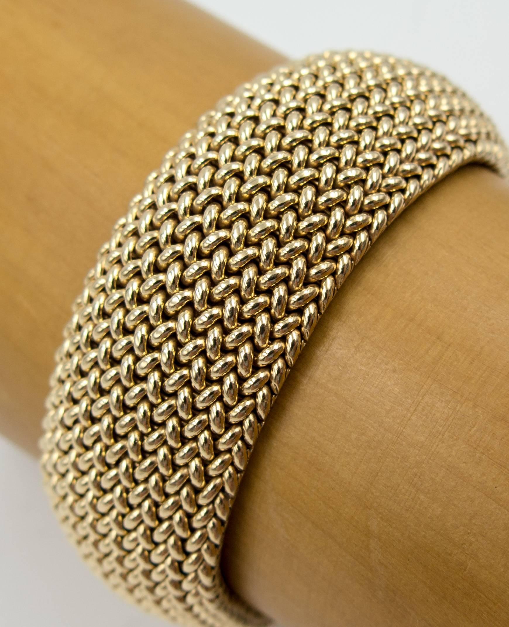 A timeless bracelet made of tiny interlocking braids of yellow gold that gracefully curve into a solid form as it's fastened onto the wrist.  It measures 7 1/2 inches in length ( slightly longer than the average size bracelet) and is 7/8" wide.