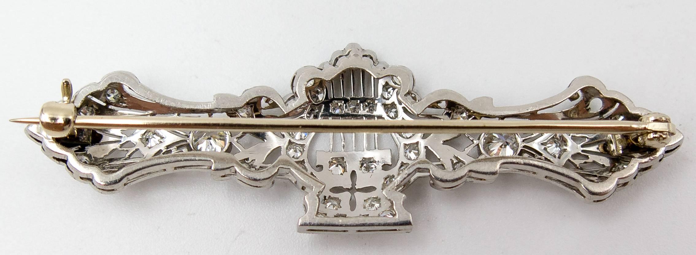 An unusual and delightful little bar pin for the symphony or string quartet lover.  A bar pin crafted in platinum measuring 2 1/4 inches in width centers a diamond set lyre flanked at top, bottom, and sides with additional diamonds.  The diamonds